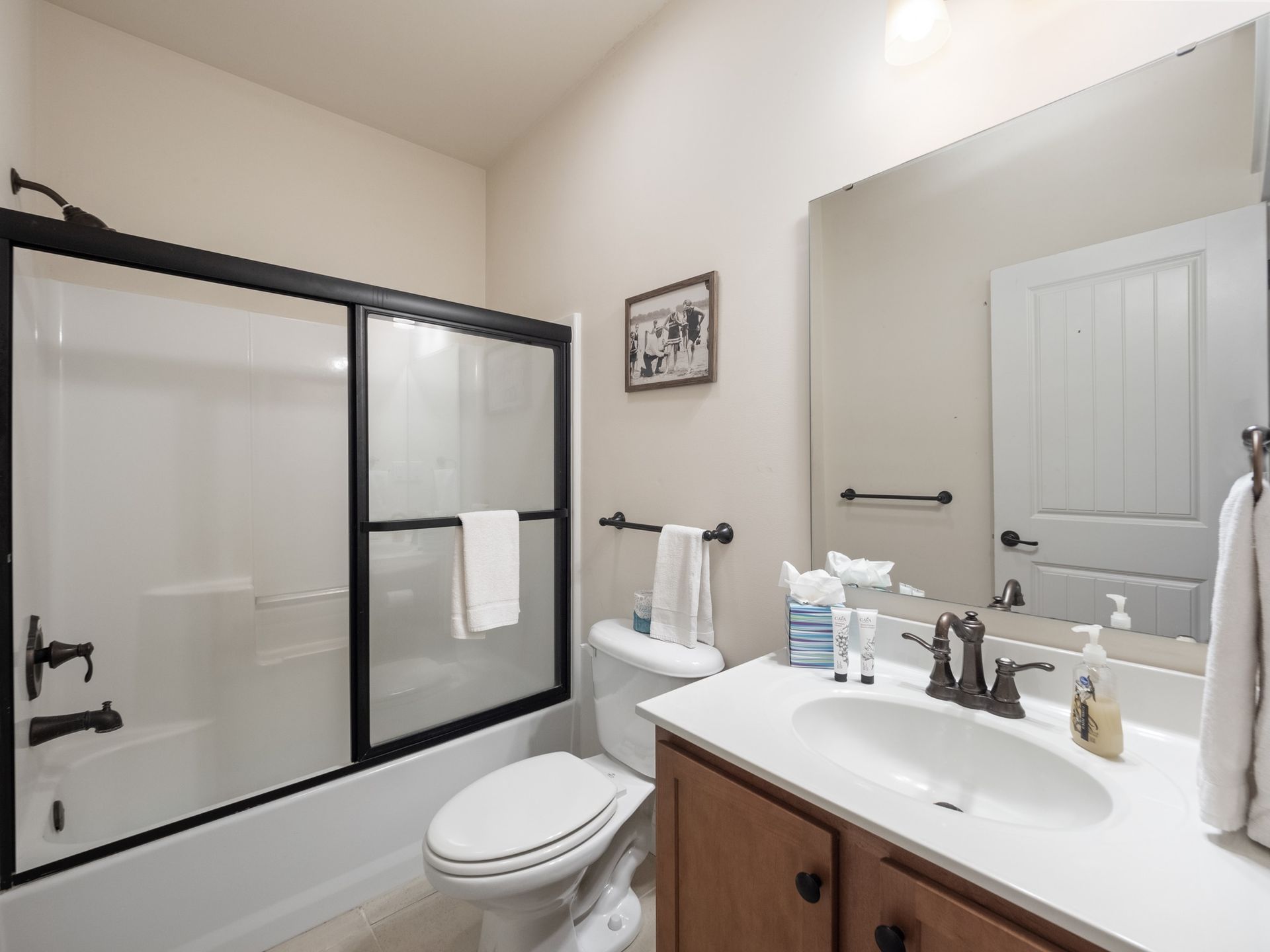 A bathroom with a toilet , sink , shower and mirror.