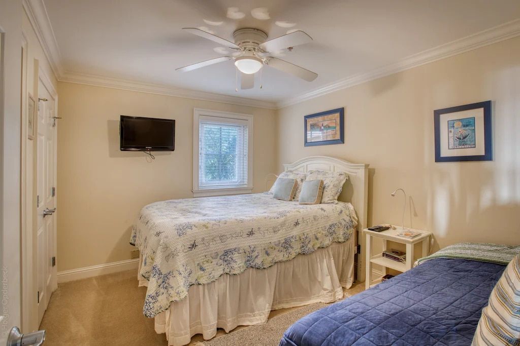 A bedroom with a king size bed , a flat screen tv , and a ceiling fan.
