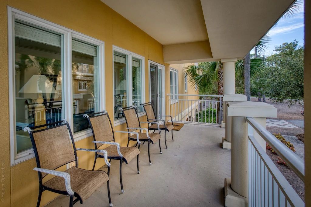 A row of chairs are sitting on a porch in front of a building.