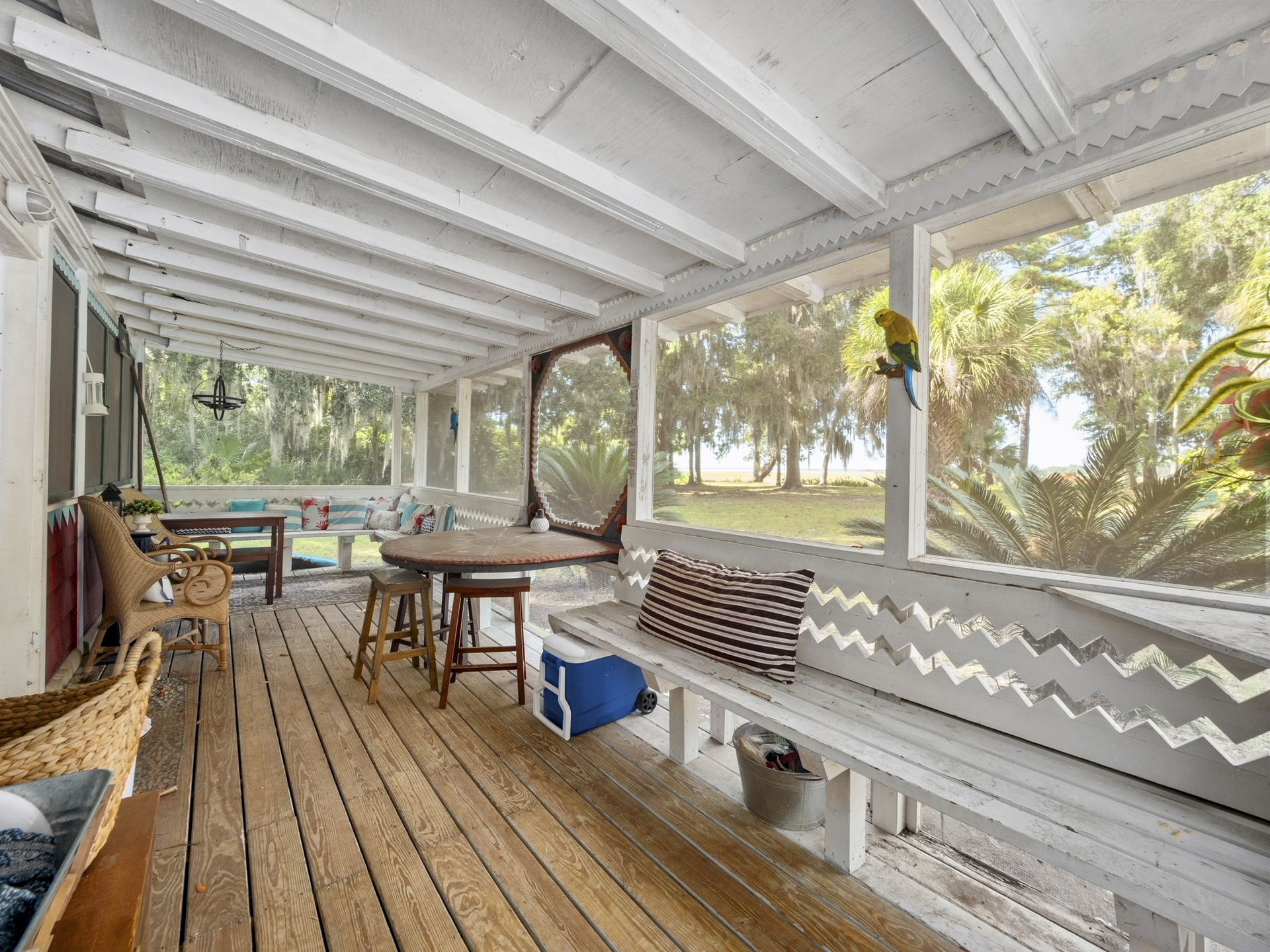 A screened in porch with a table and chairs and a bench.