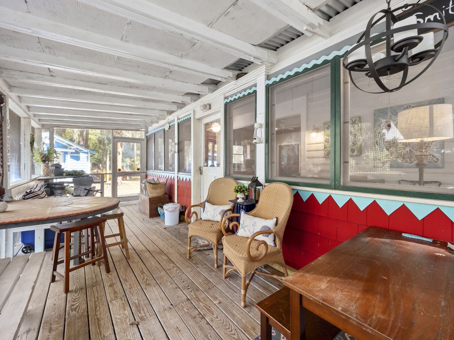 A porch with chairs , a table and a chandelier.
