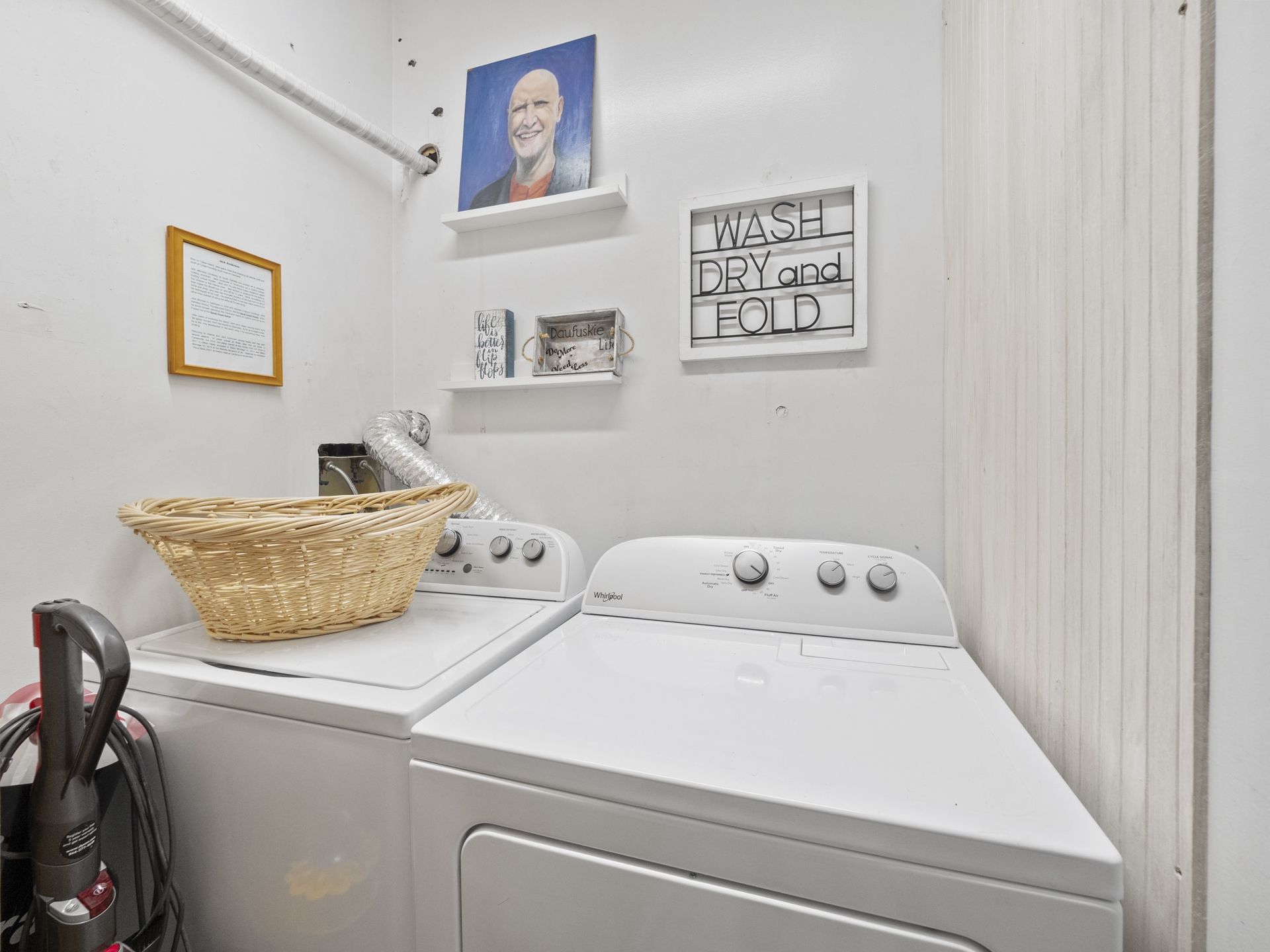 A laundry room with a washer and dryer and a vacuum cleaner.