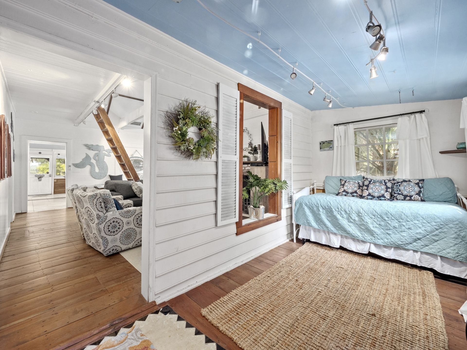 A living room with a day bed and a blue ceiling.