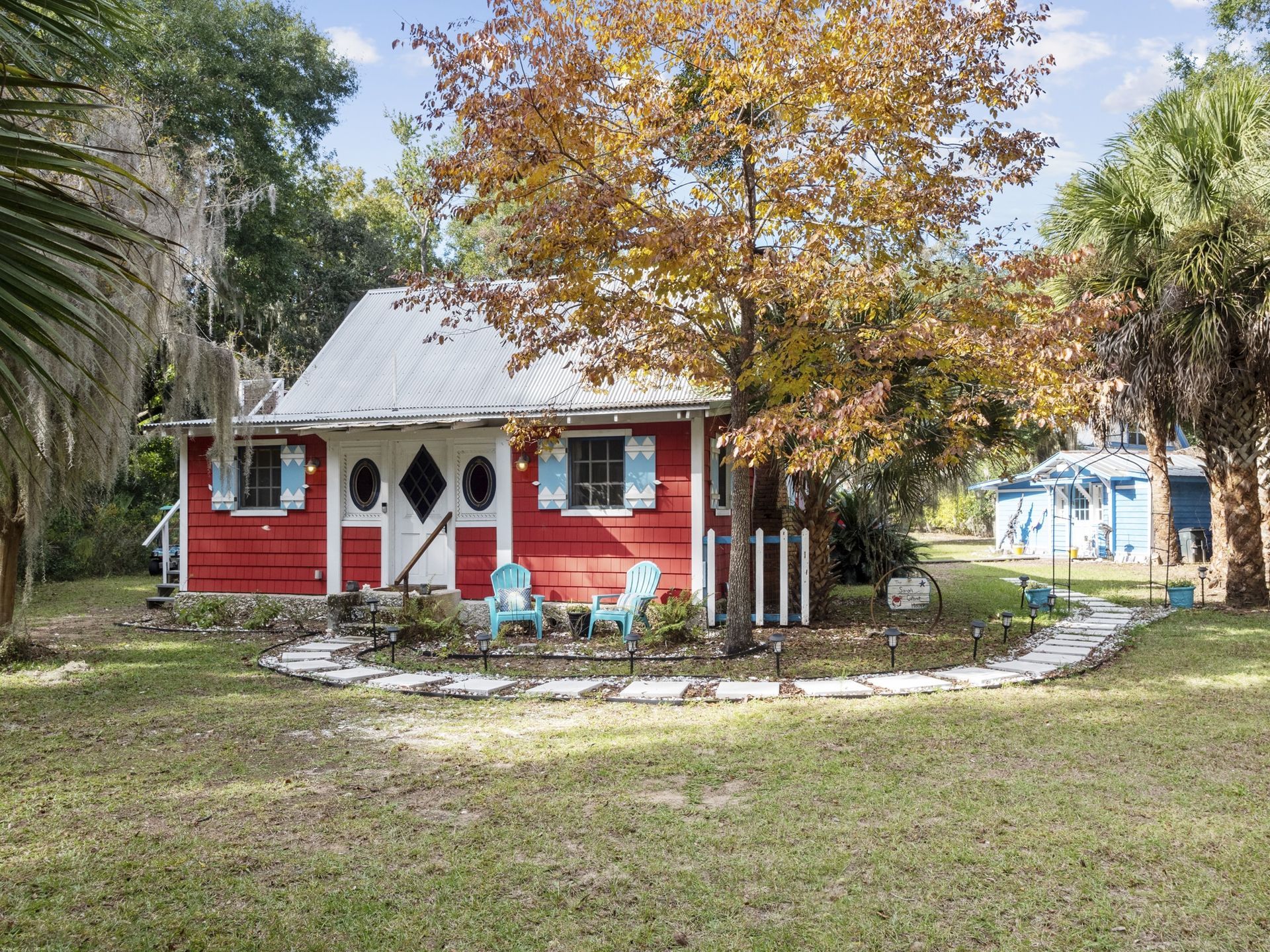 A small red house with blue chairs in front of it