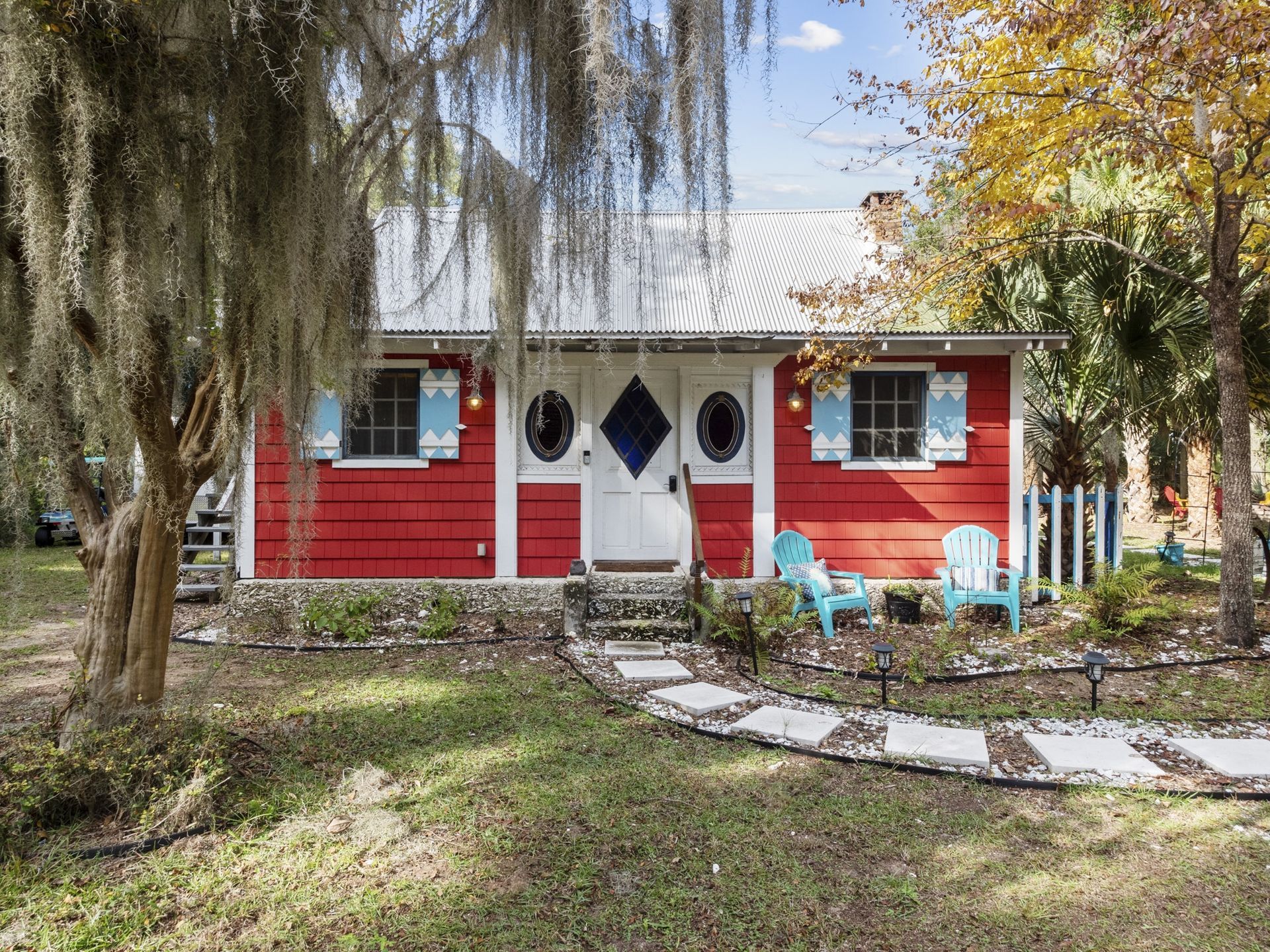 A red house with blue chairs in front of it.
