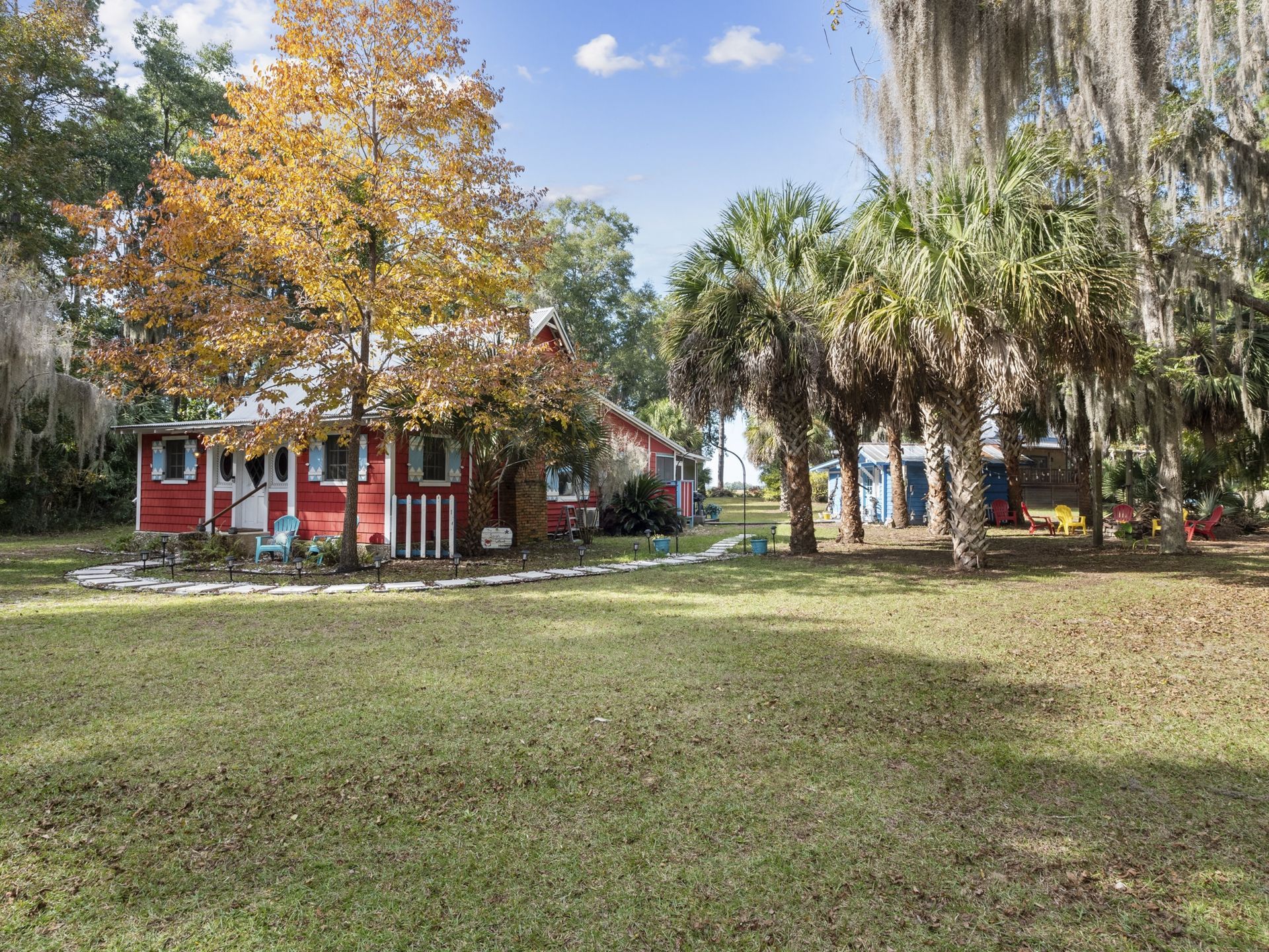A red house is surrounded by palm trees and spanish moss.