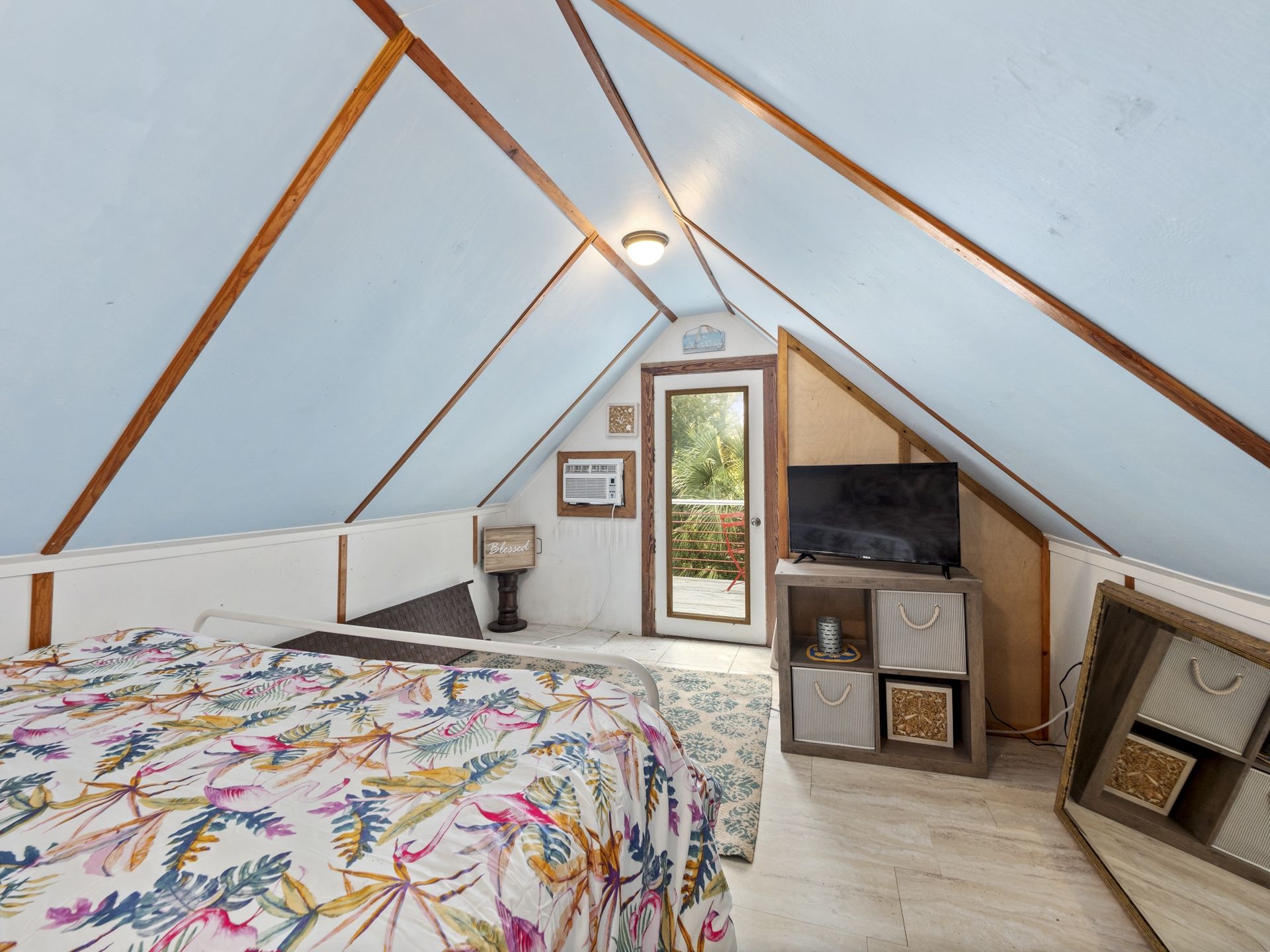 A bedroom with a bed and a television in the attic.