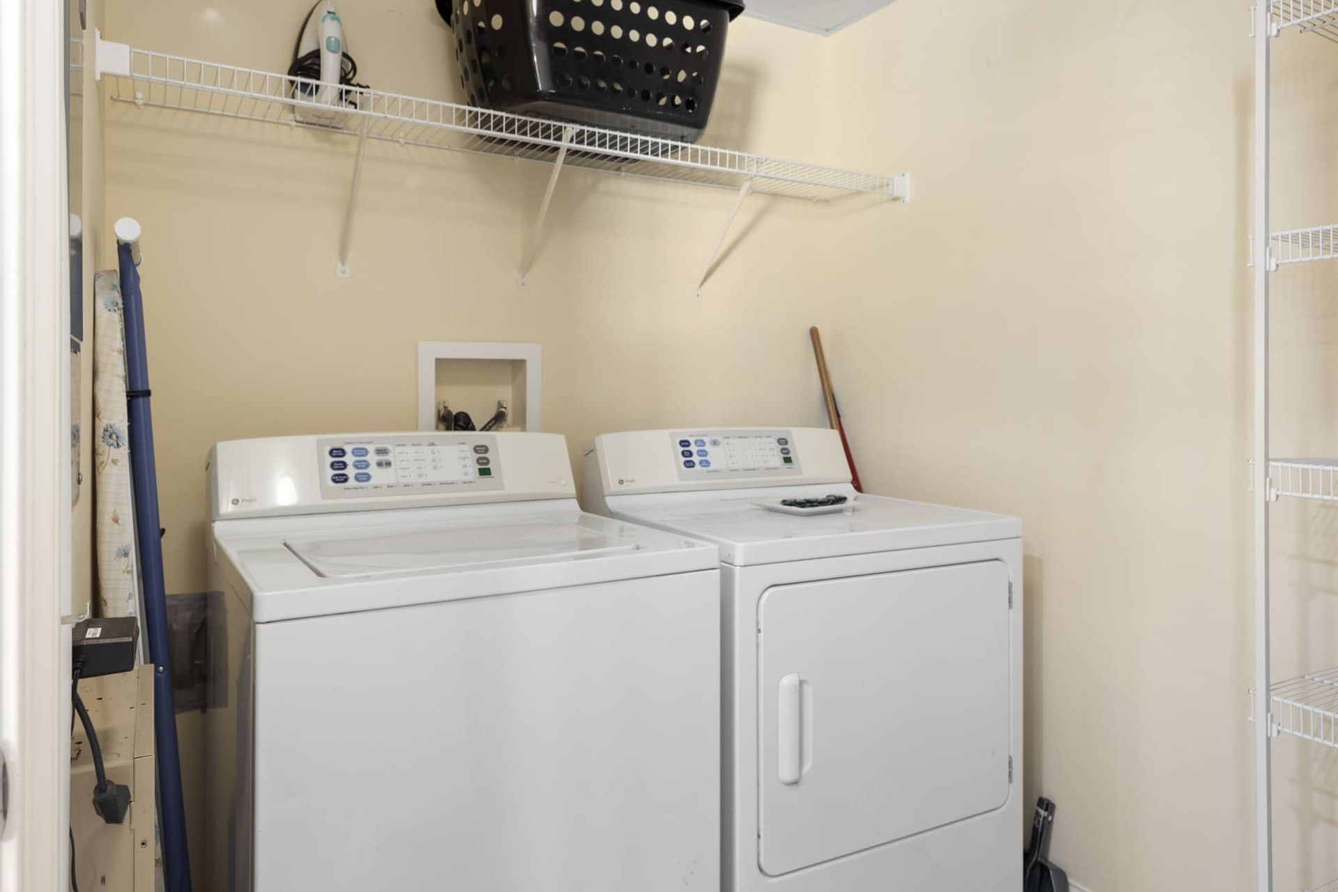 A laundry room with a washer and dryer and a basket on the wall.