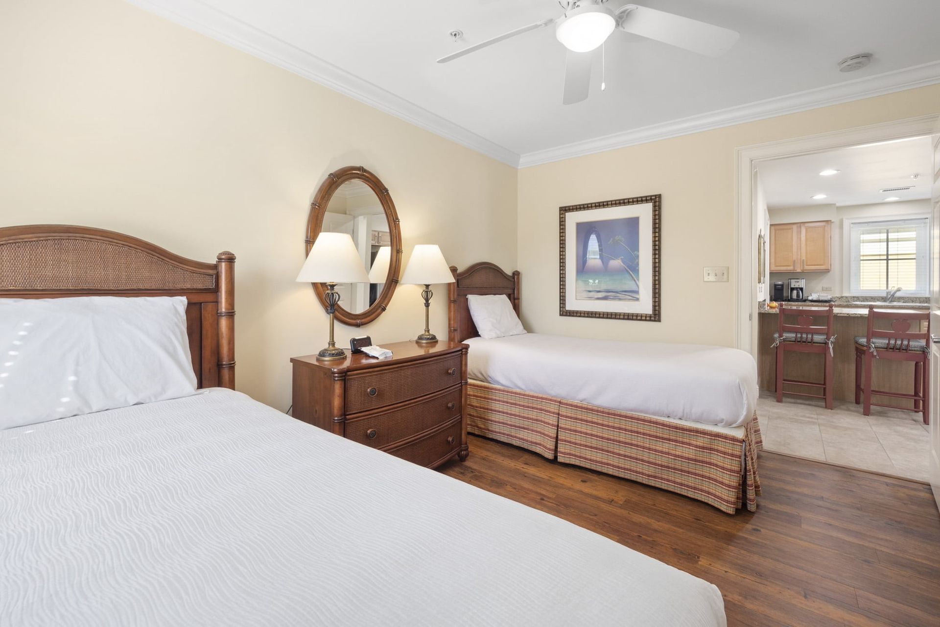 A bedroom with two beds , a dresser , a mirror and a ceiling fan.