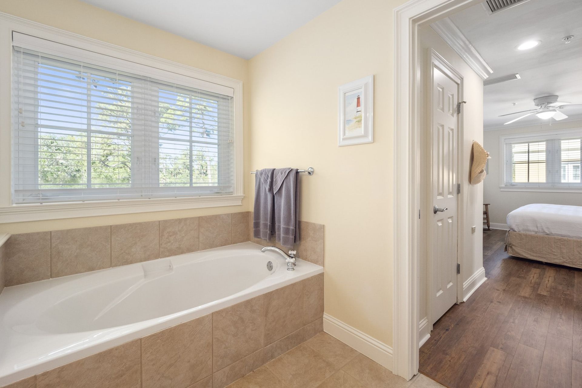 A bathroom with a tub and a window next to a bedroom.