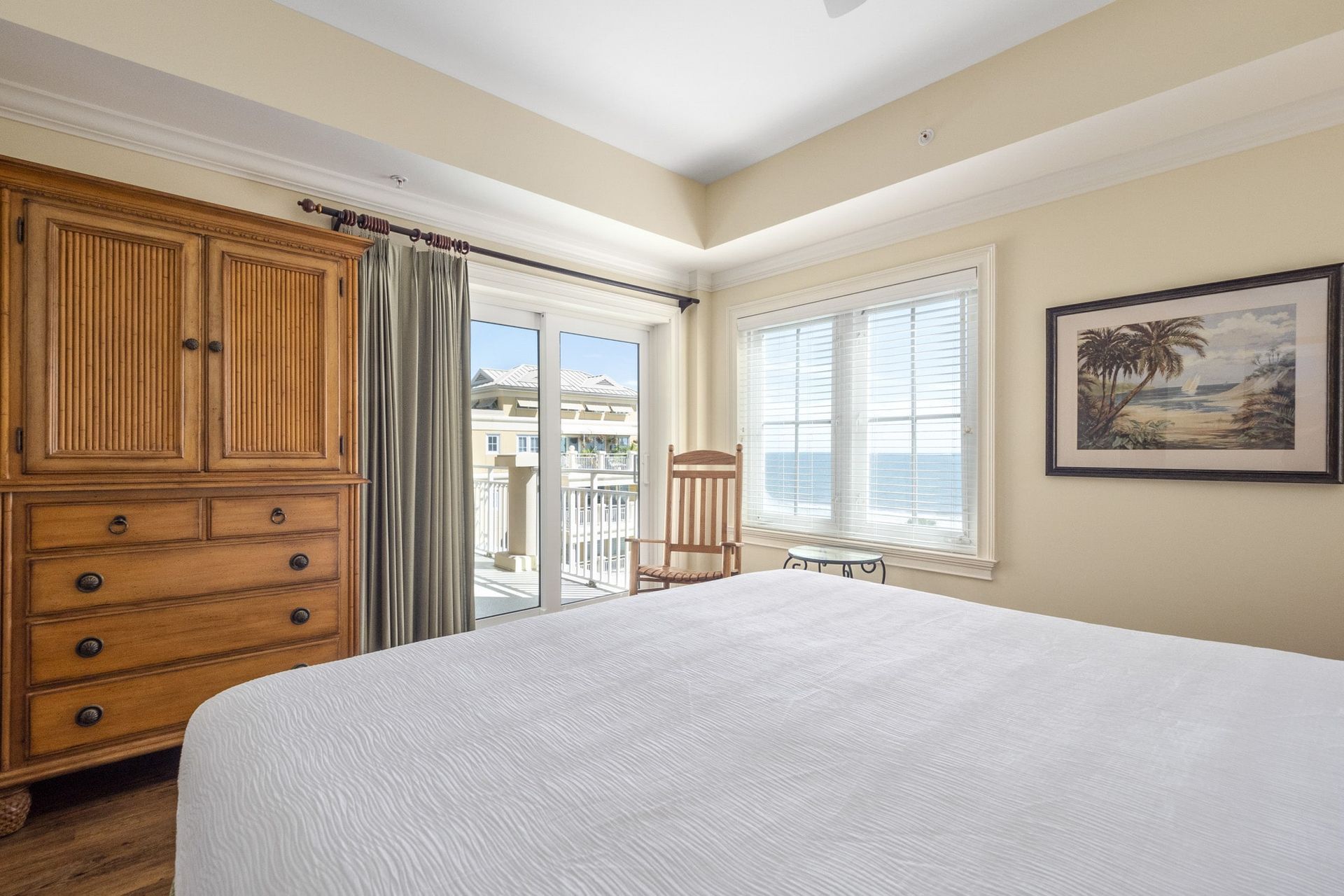 A bedroom with a king size bed , dresser , chair and window.
