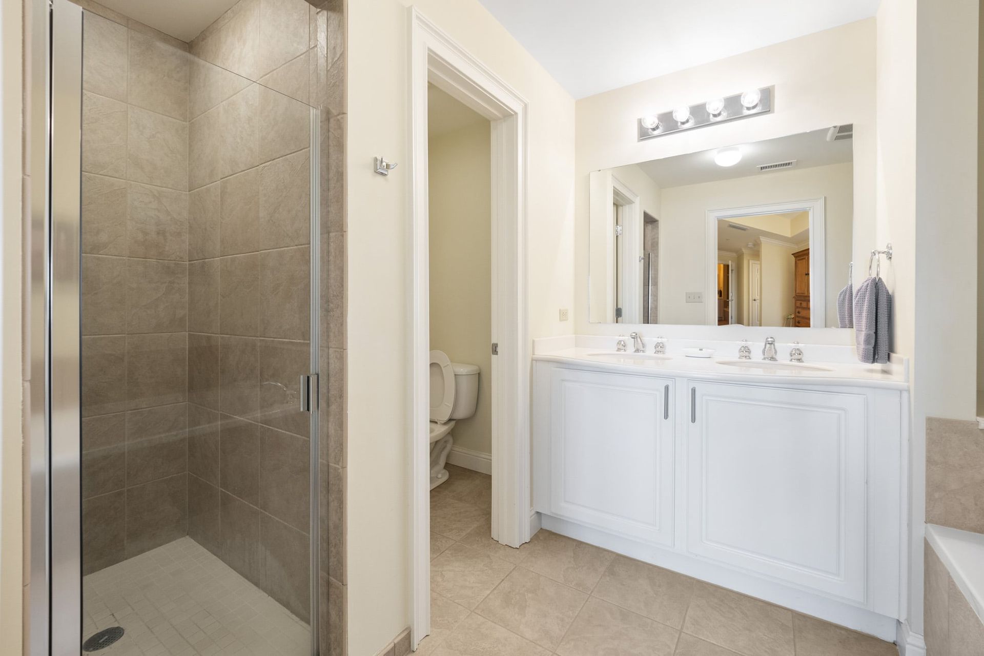 A bathroom with two sinks , a toilet , and a walk in shower.