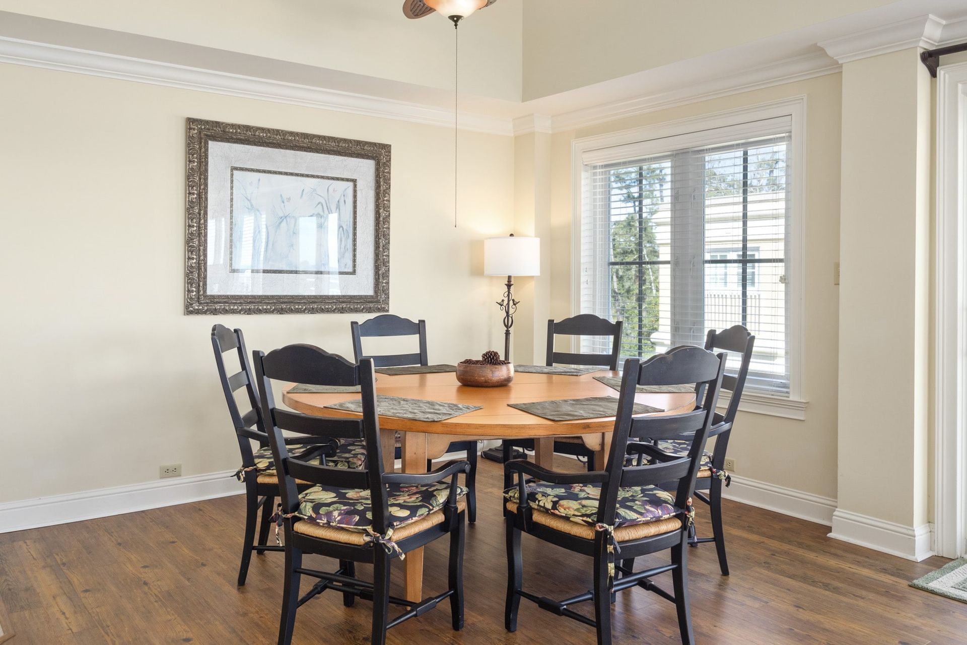 A dining room with a table and chairs and a picture on the wall.