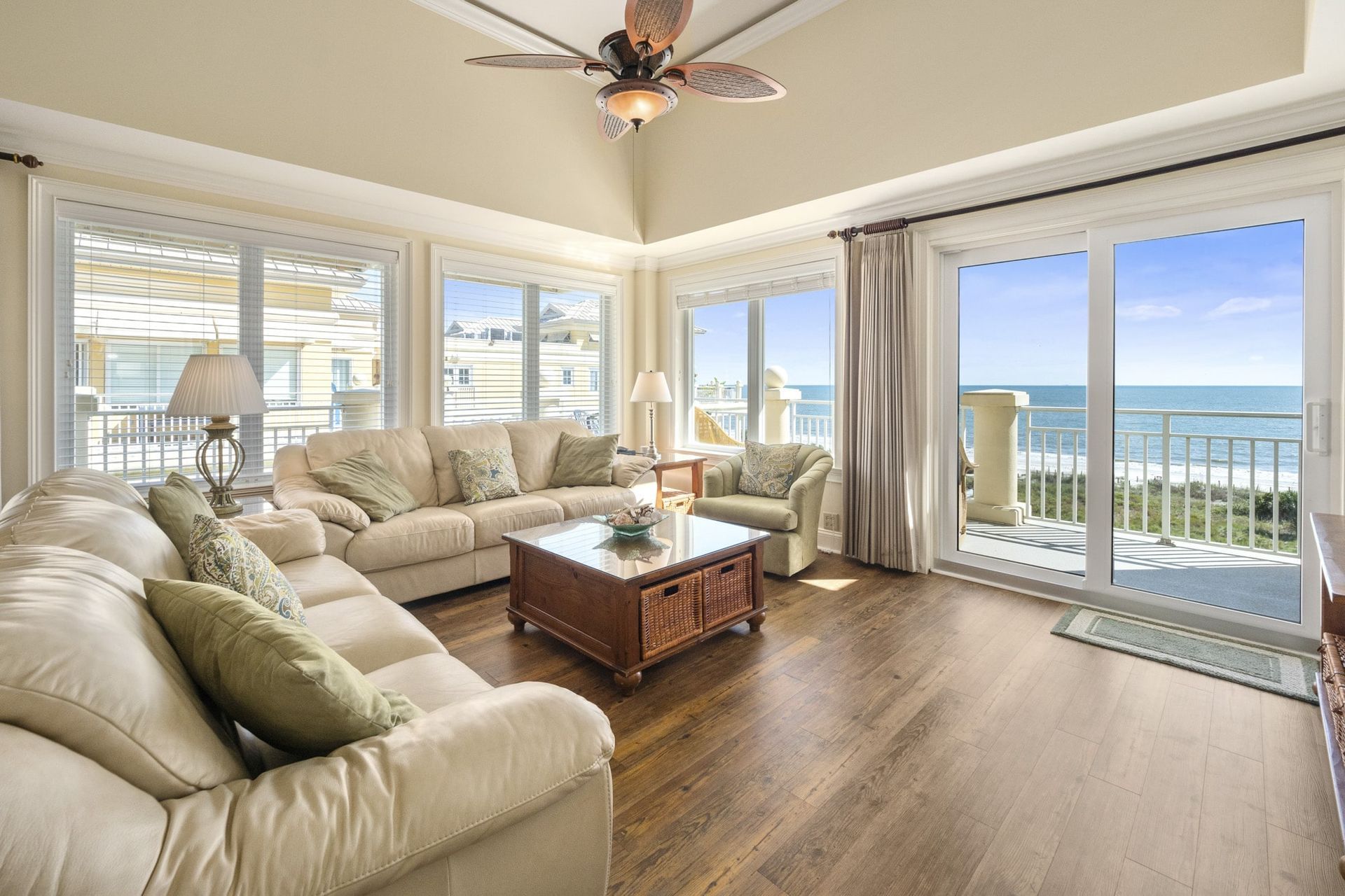 A living room filled with furniture and a ceiling fan with a view of the ocean.