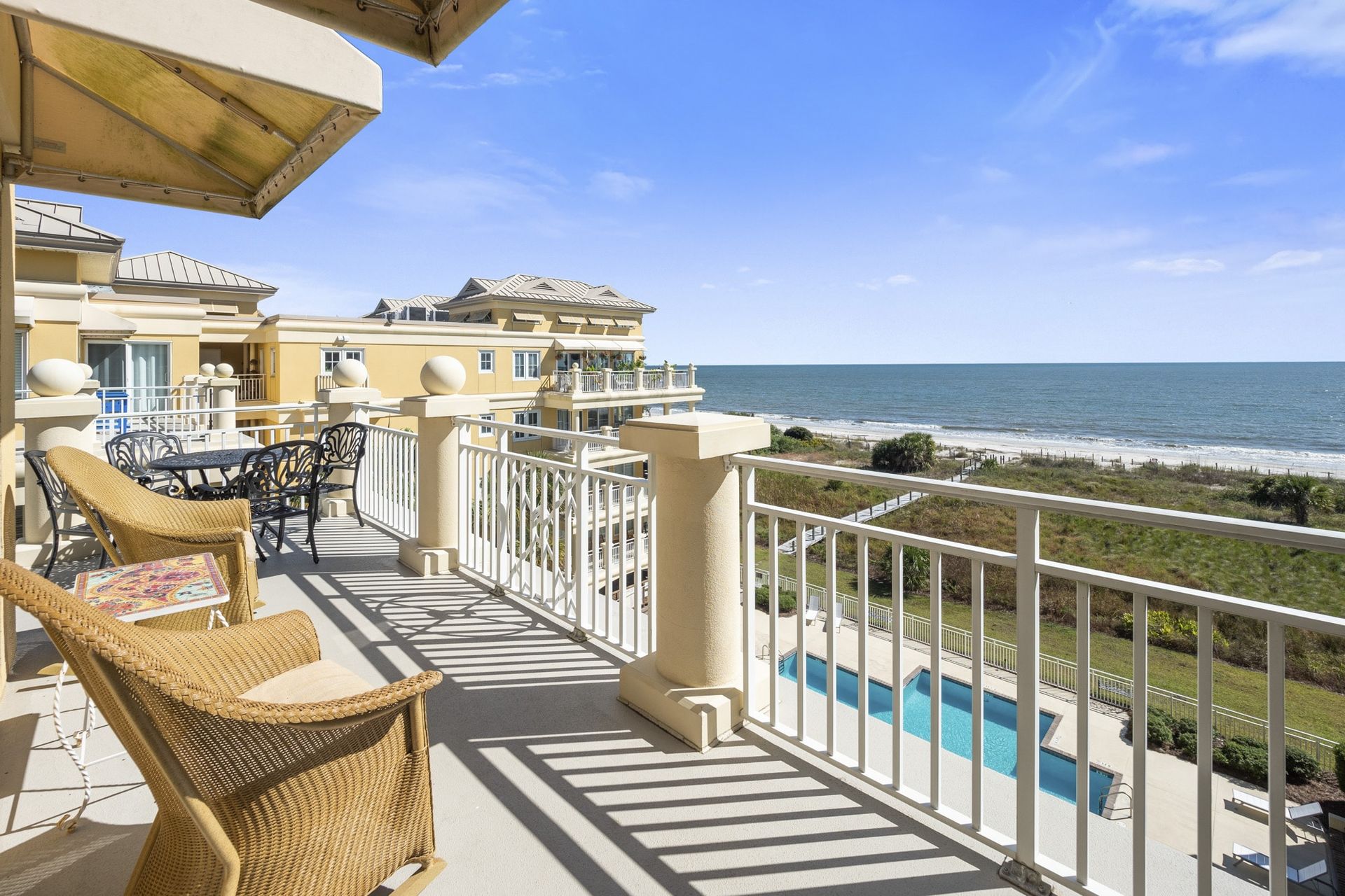 There is a balcony with a view of the ocean and a pool.