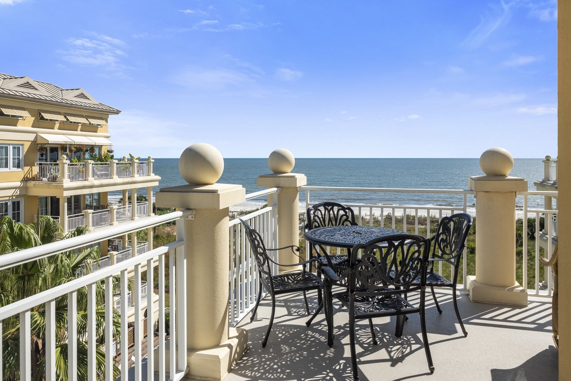 A balcony with a table and chairs overlooking the ocean.