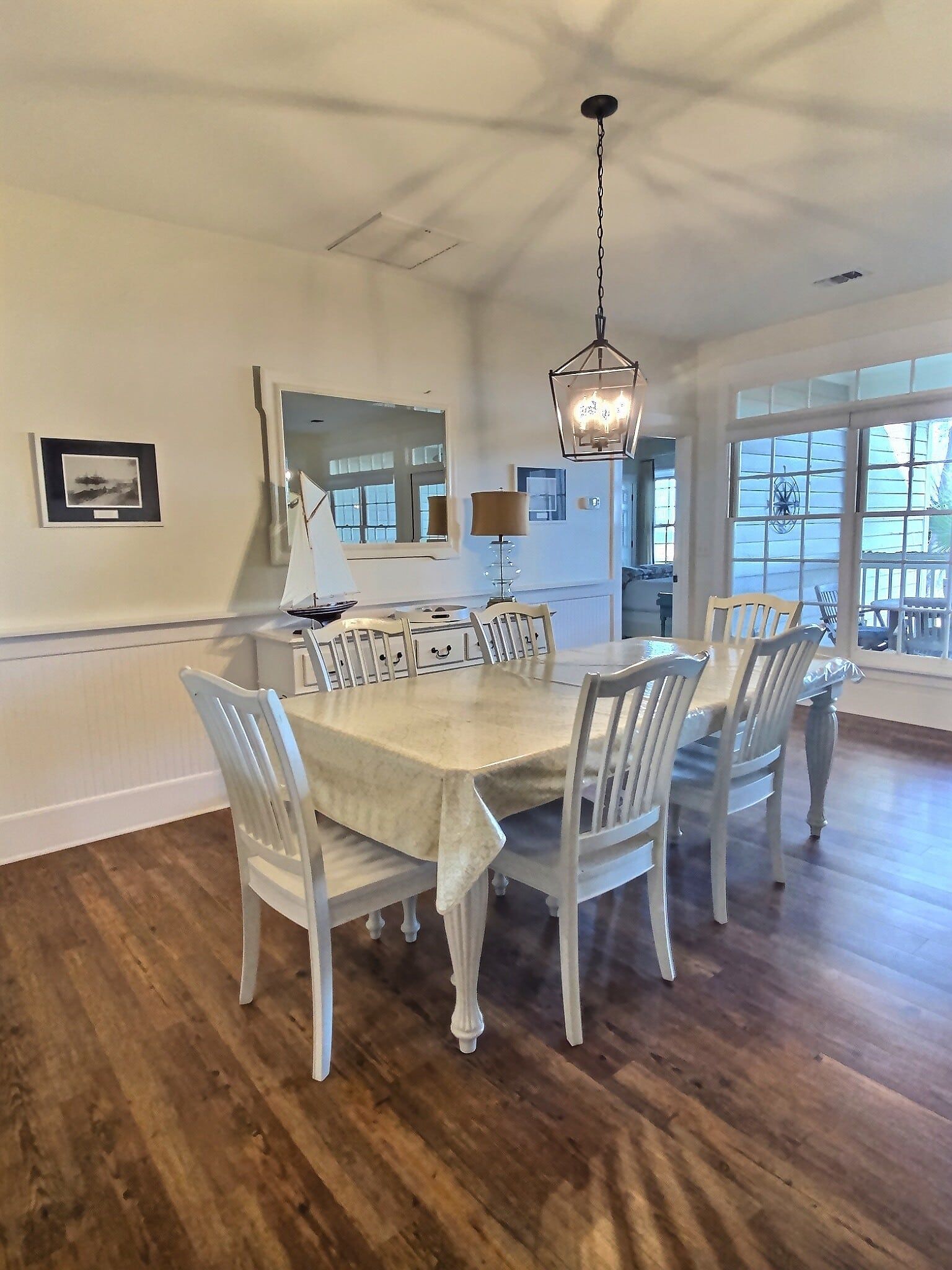 A dining room with a table and chairs and a sailboat on the wall.