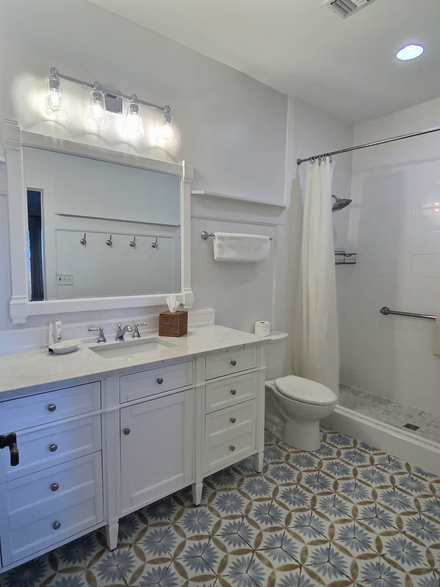 A bathroom with a sink , toilet , shower and mirror.