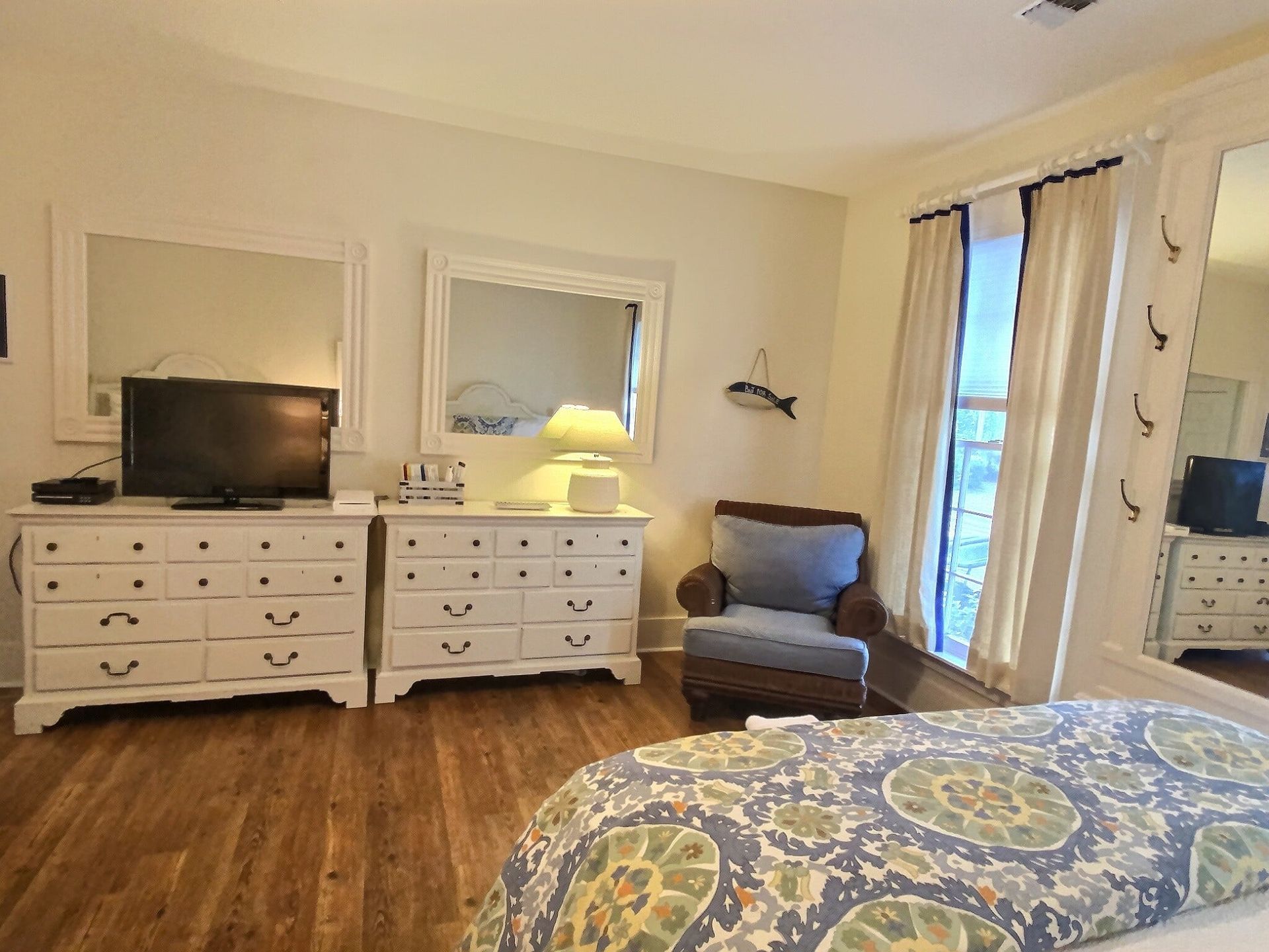 A bedroom with a bed , dresser , chair and television