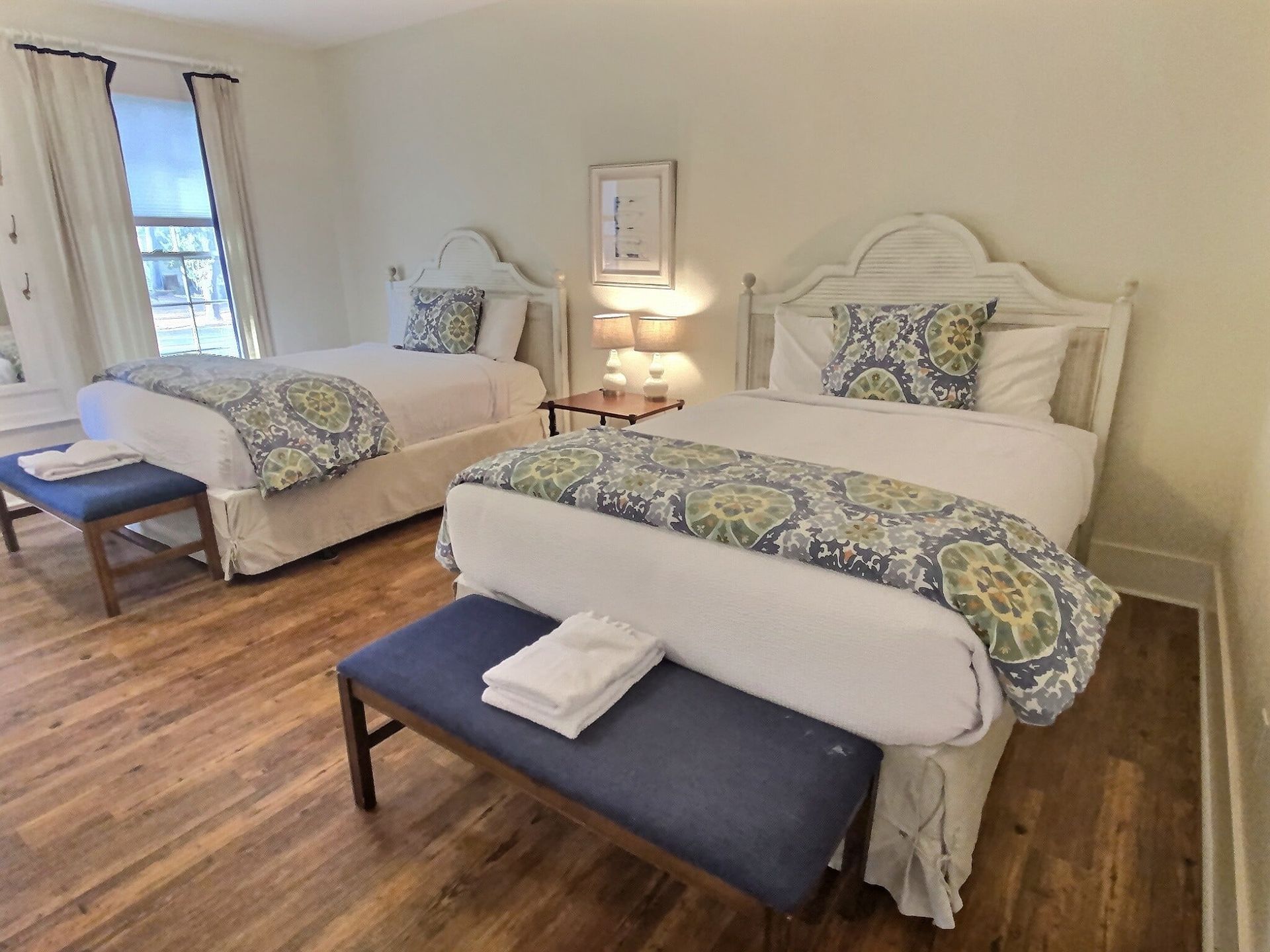 A hotel room with two beds and a bench