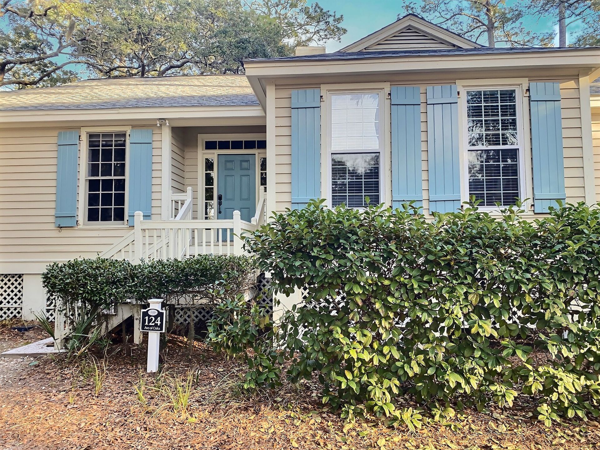 The front of a house with blue shutters and a white fence.