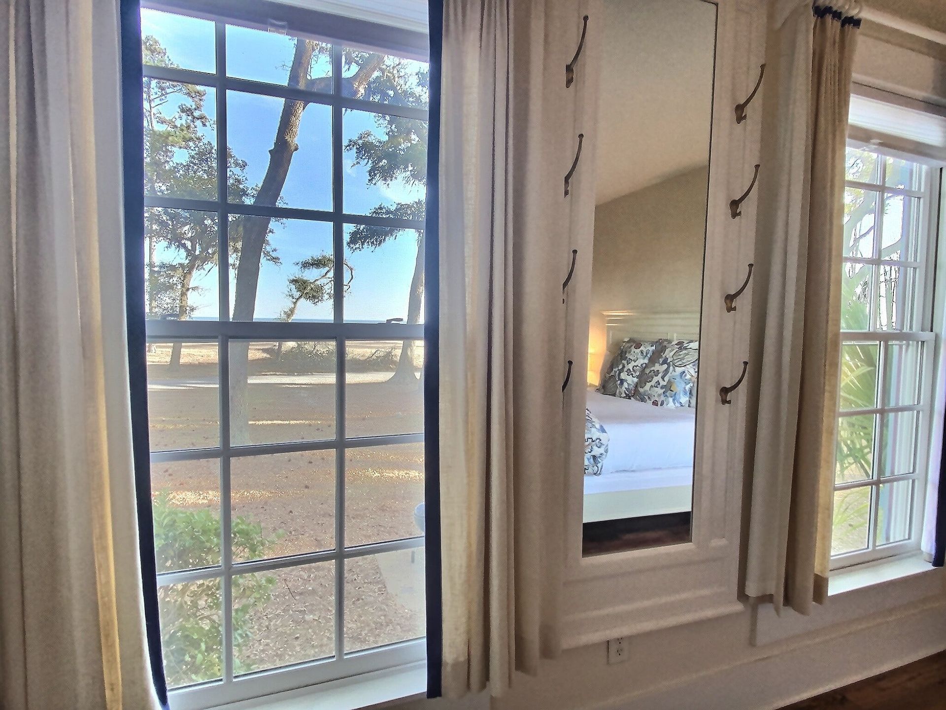 A bedroom with two windows and a mirror on the wall.