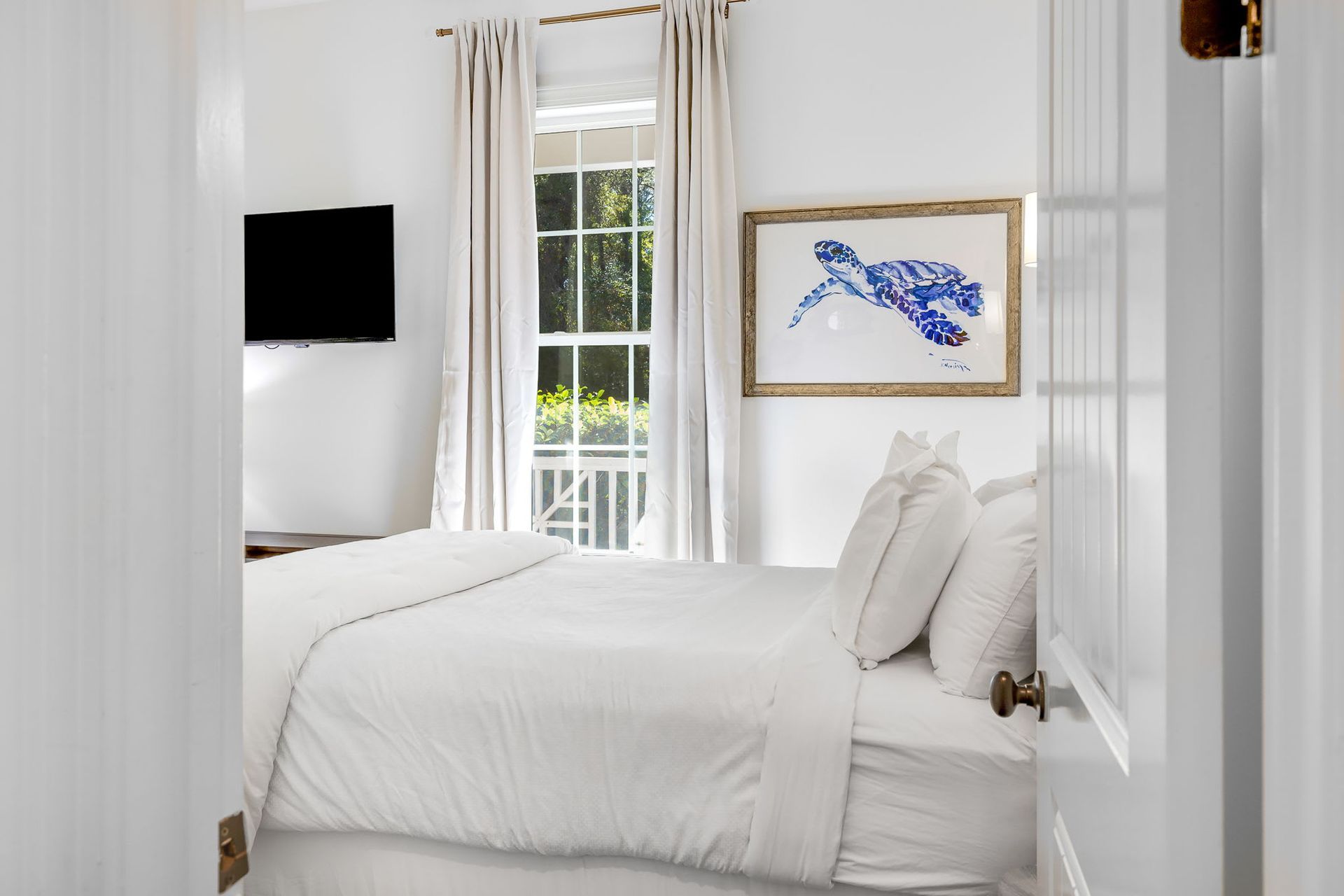 A bedroom with a bed , television , and picture on the wall.