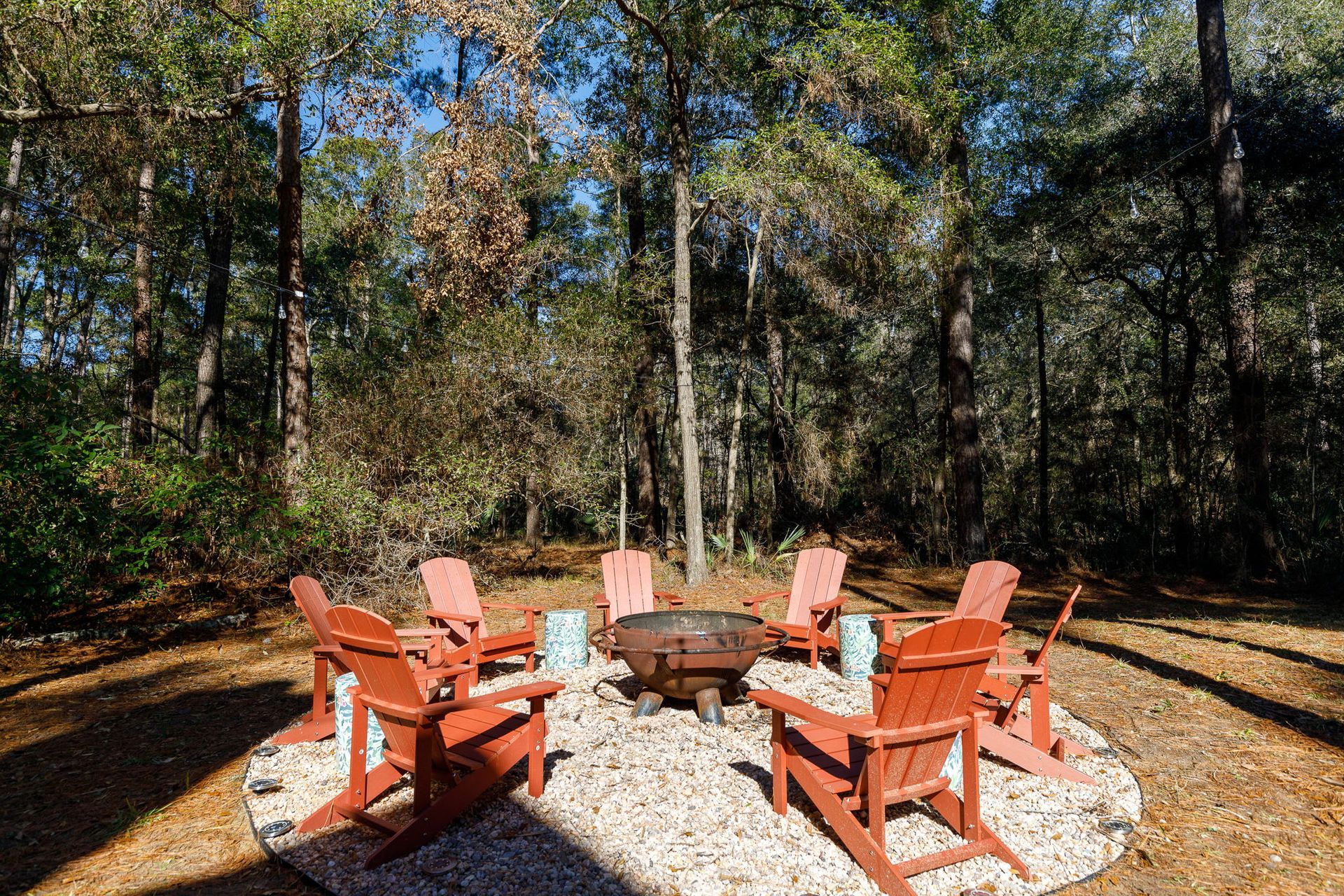 A group of chairs are sitting around a fire pit in the middle of a forest.