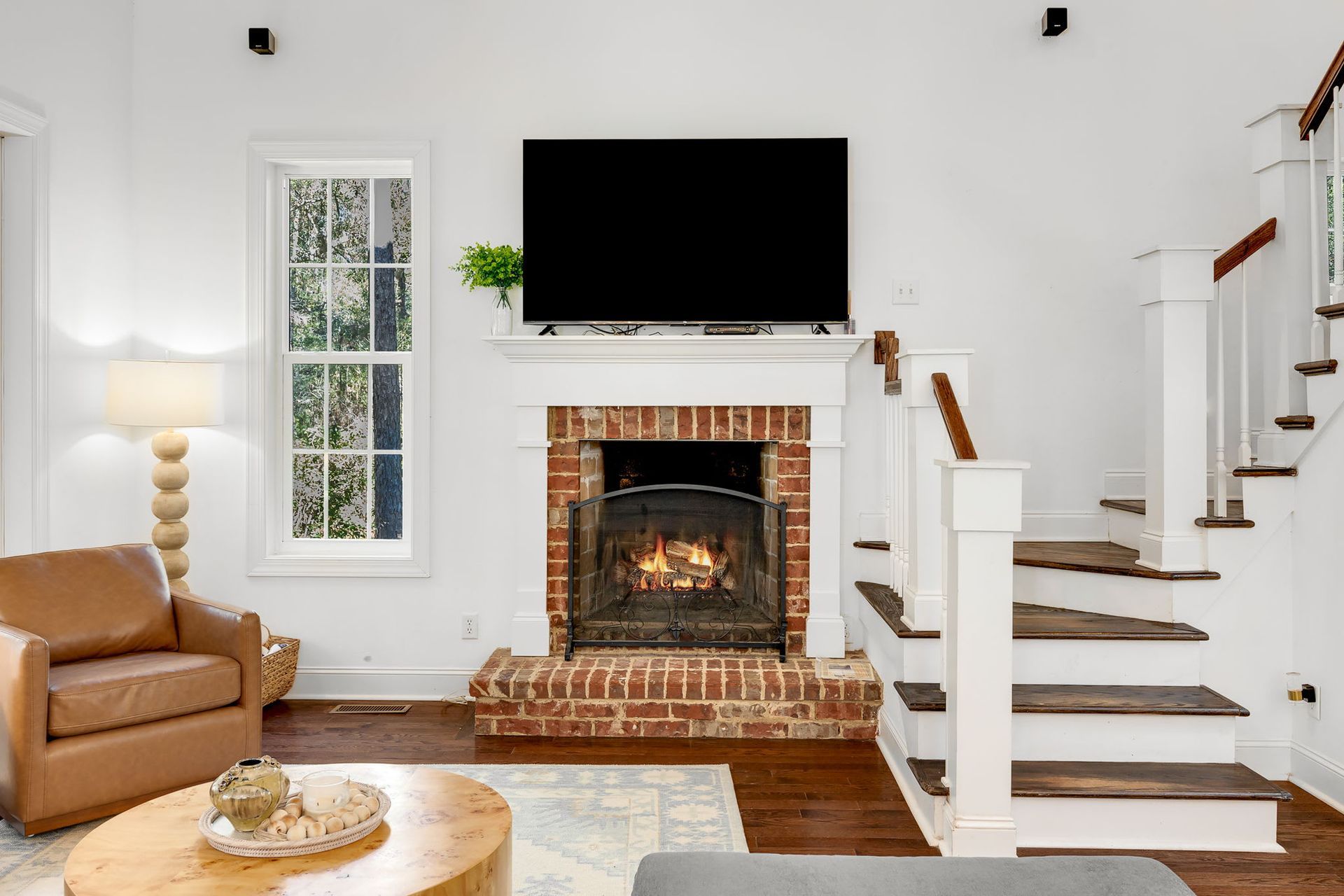 A living room with a fireplace , stairs and a flat screen tv.