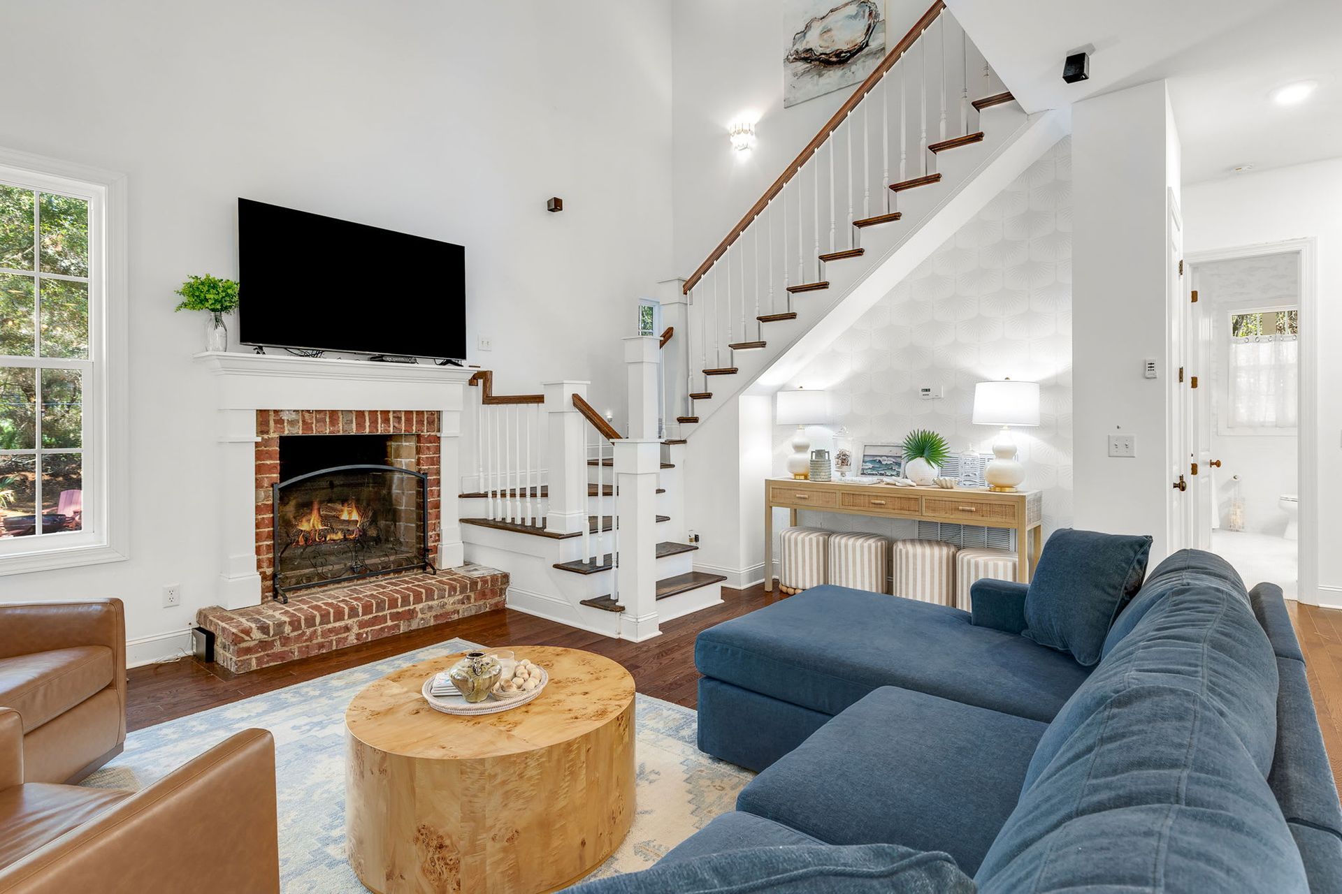A living room with a blue couch , stairs , fireplace and television.