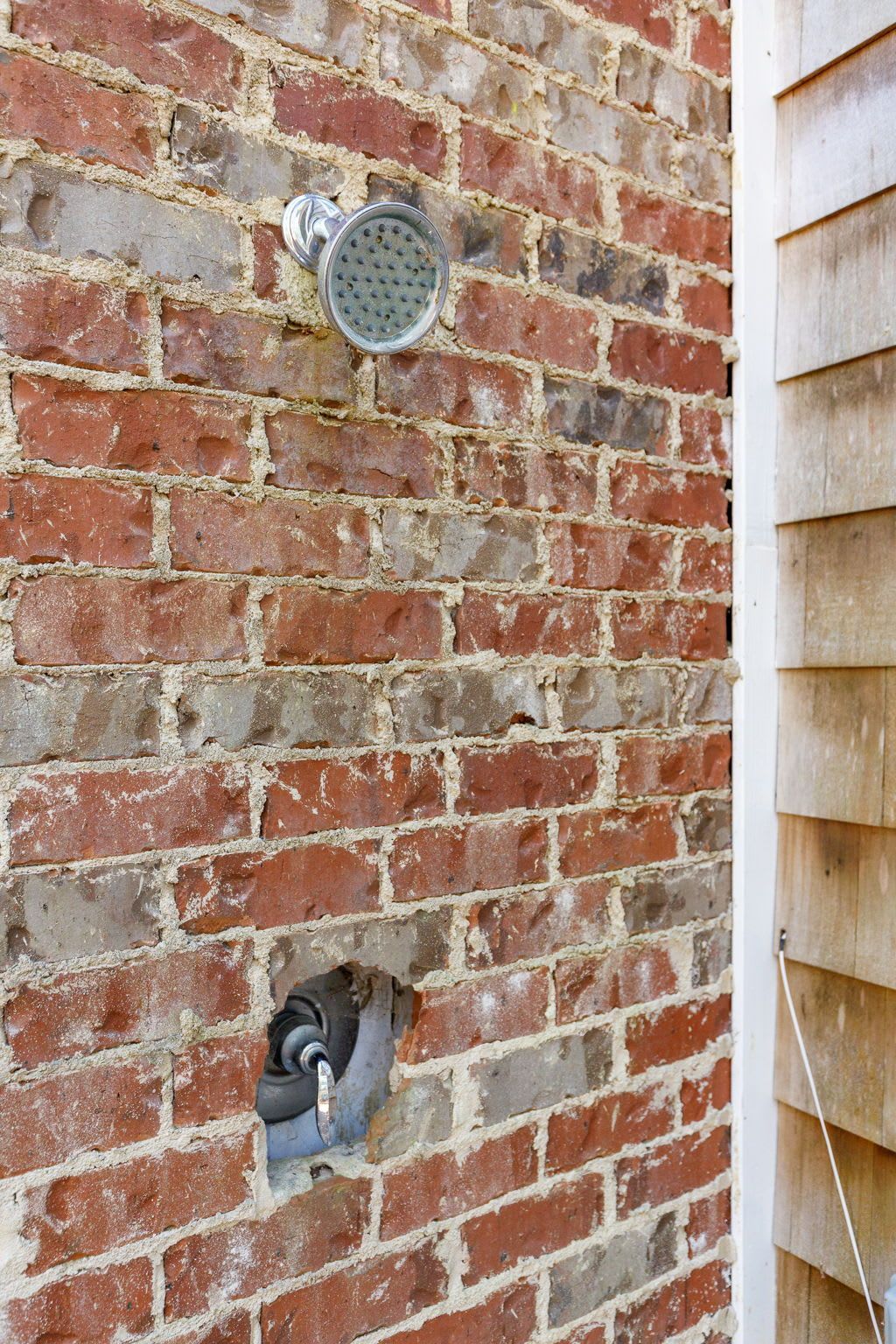 A brick wall with a shower head on it