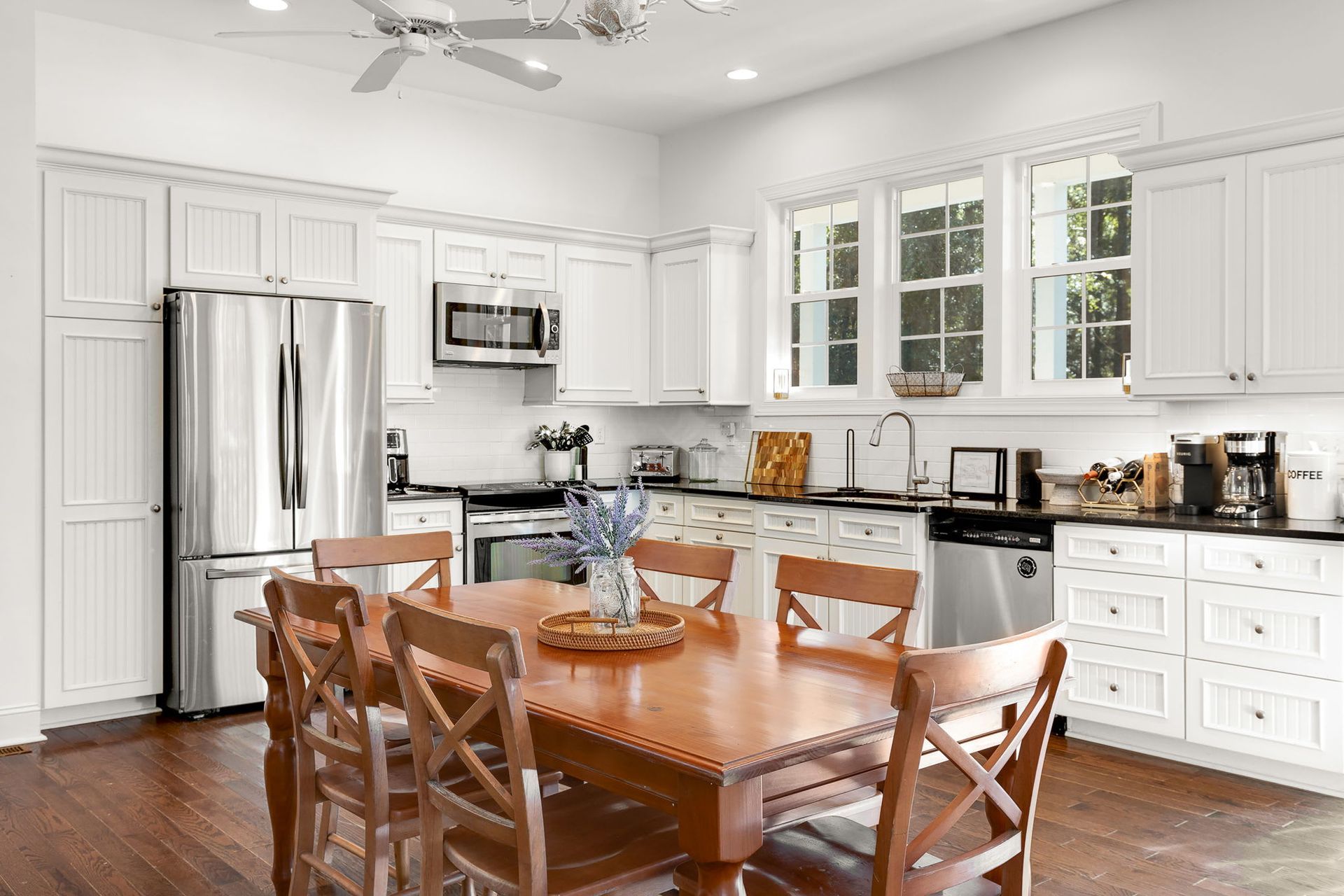 A kitchen with a wooden table and chairs and stainless steel appliances.