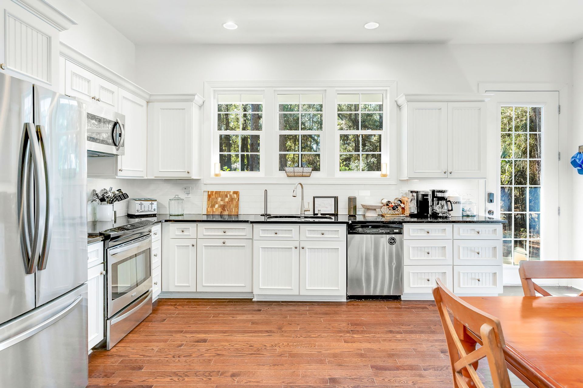 A kitchen with white cabinets , stainless steel appliances , and hardwood floors.