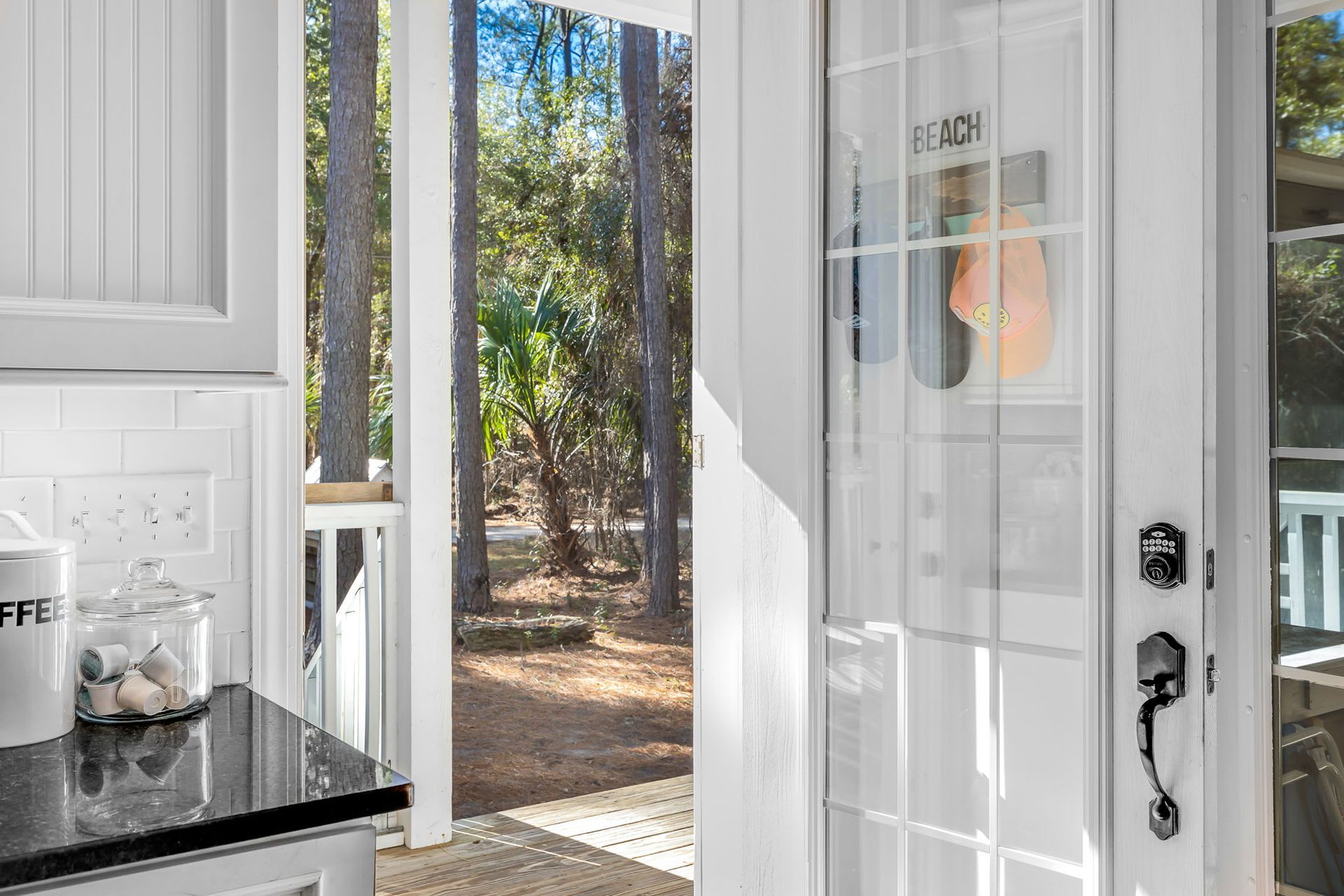 A kitchen with a sliding glass door leading to a porch with trees in the background.