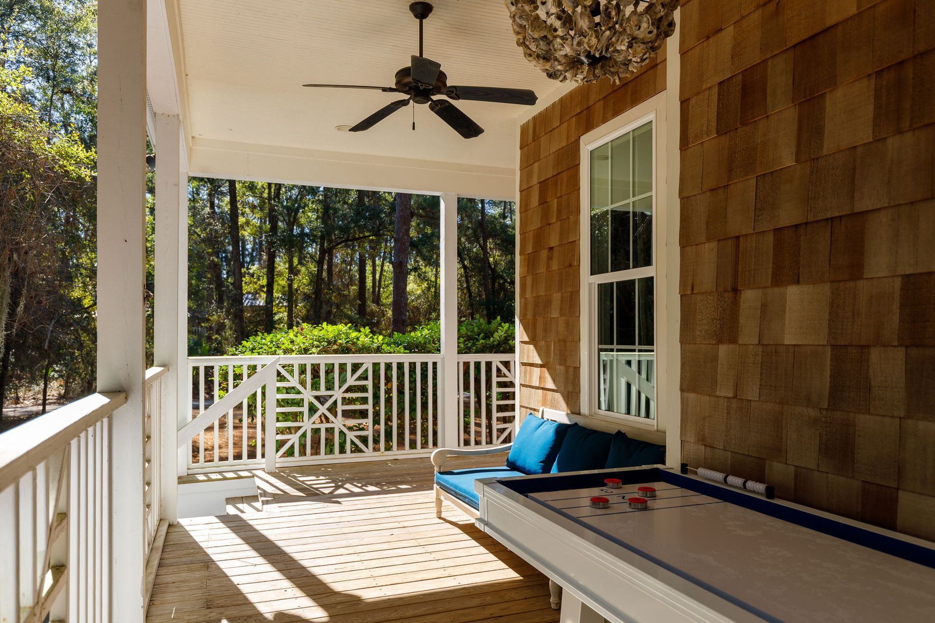 A porch with a table and a ceiling fan.