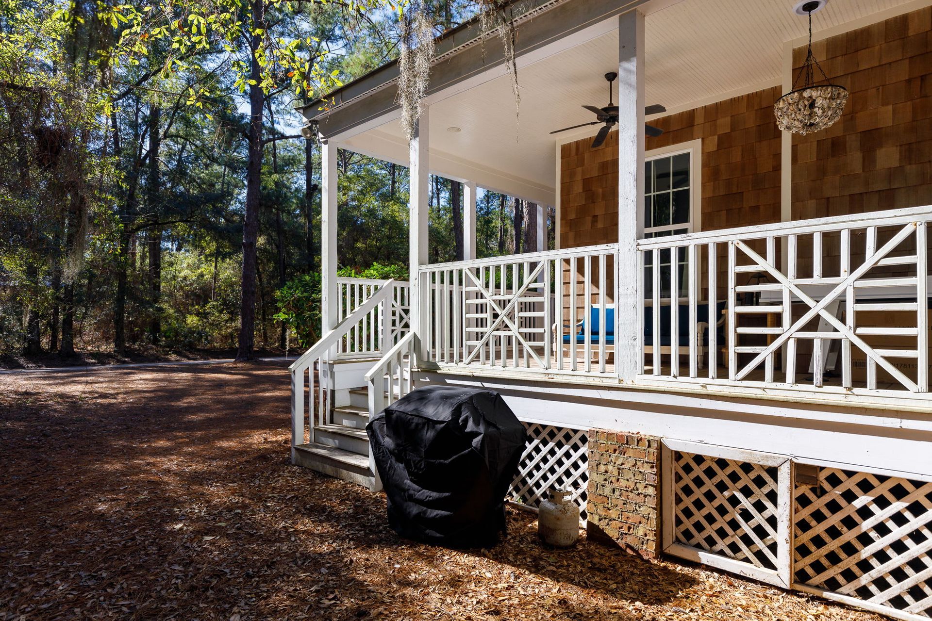 A black grill cover is sitting on a porch next to a house.
