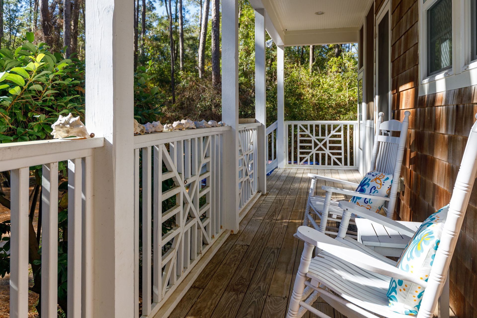There are two rocking chairs on the porch of a house.