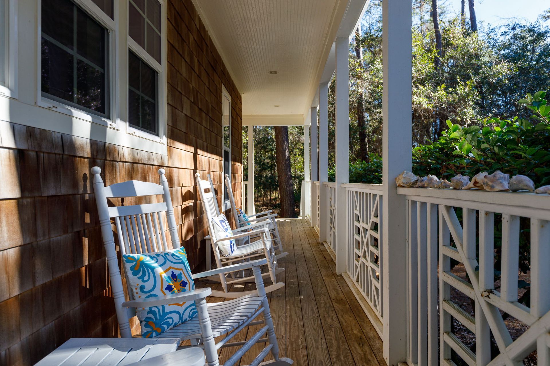 There are many rocking chairs on the porch of a house.