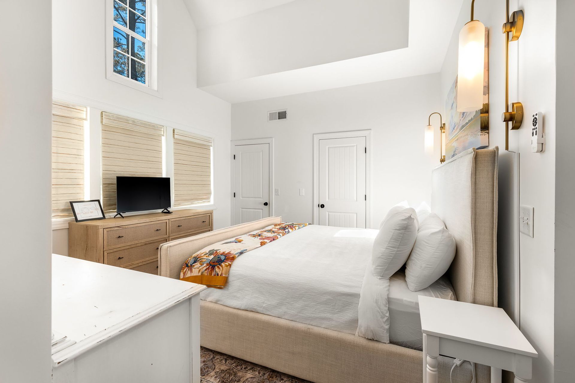 A bedroom with a large bed , dresser , nightstand and television.