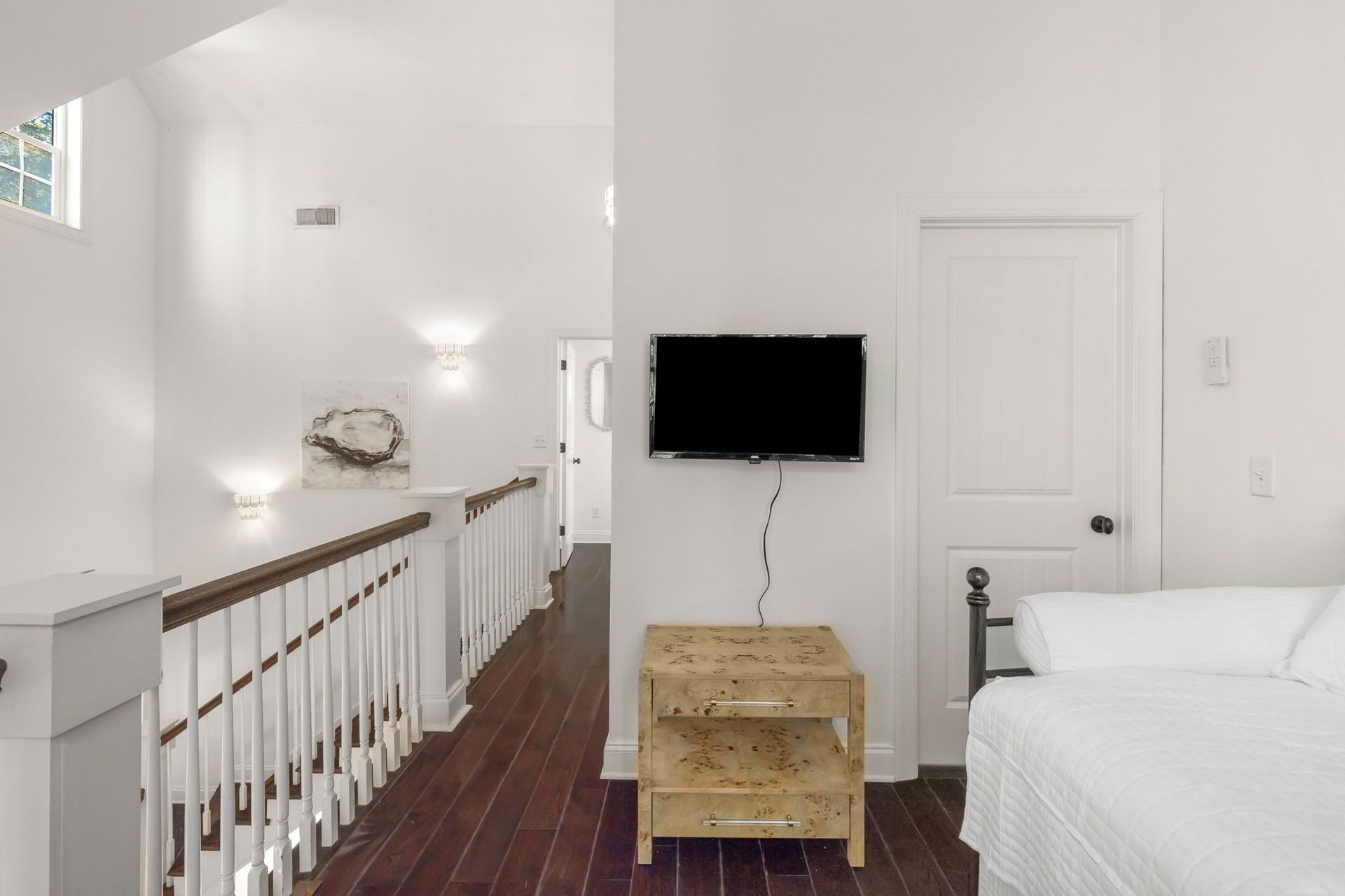 A bedroom with a bed and a television on the wall.