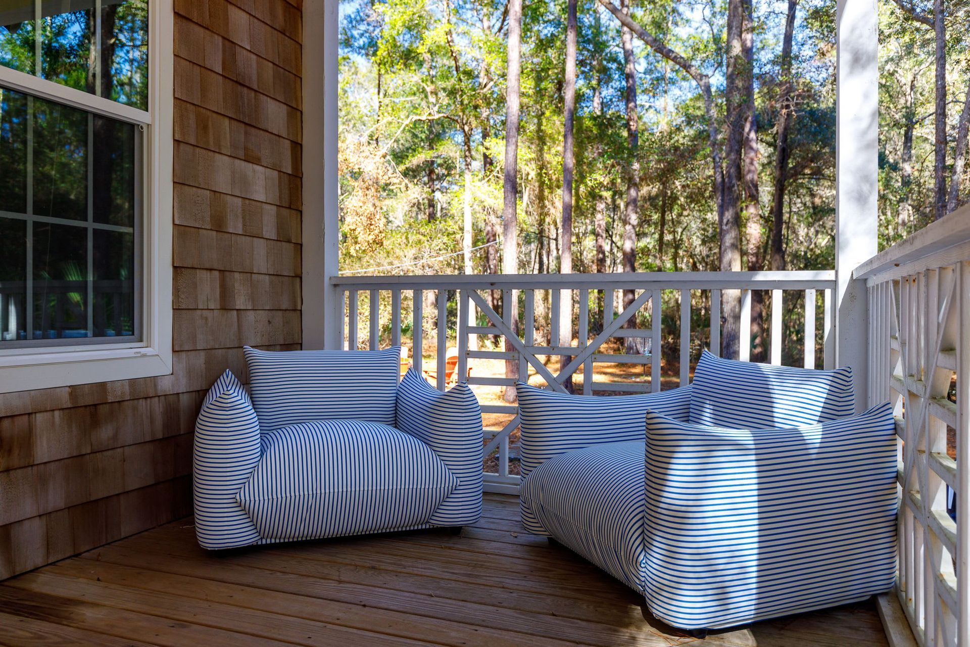 Two chairs are sitting on a porch with trees in the background.