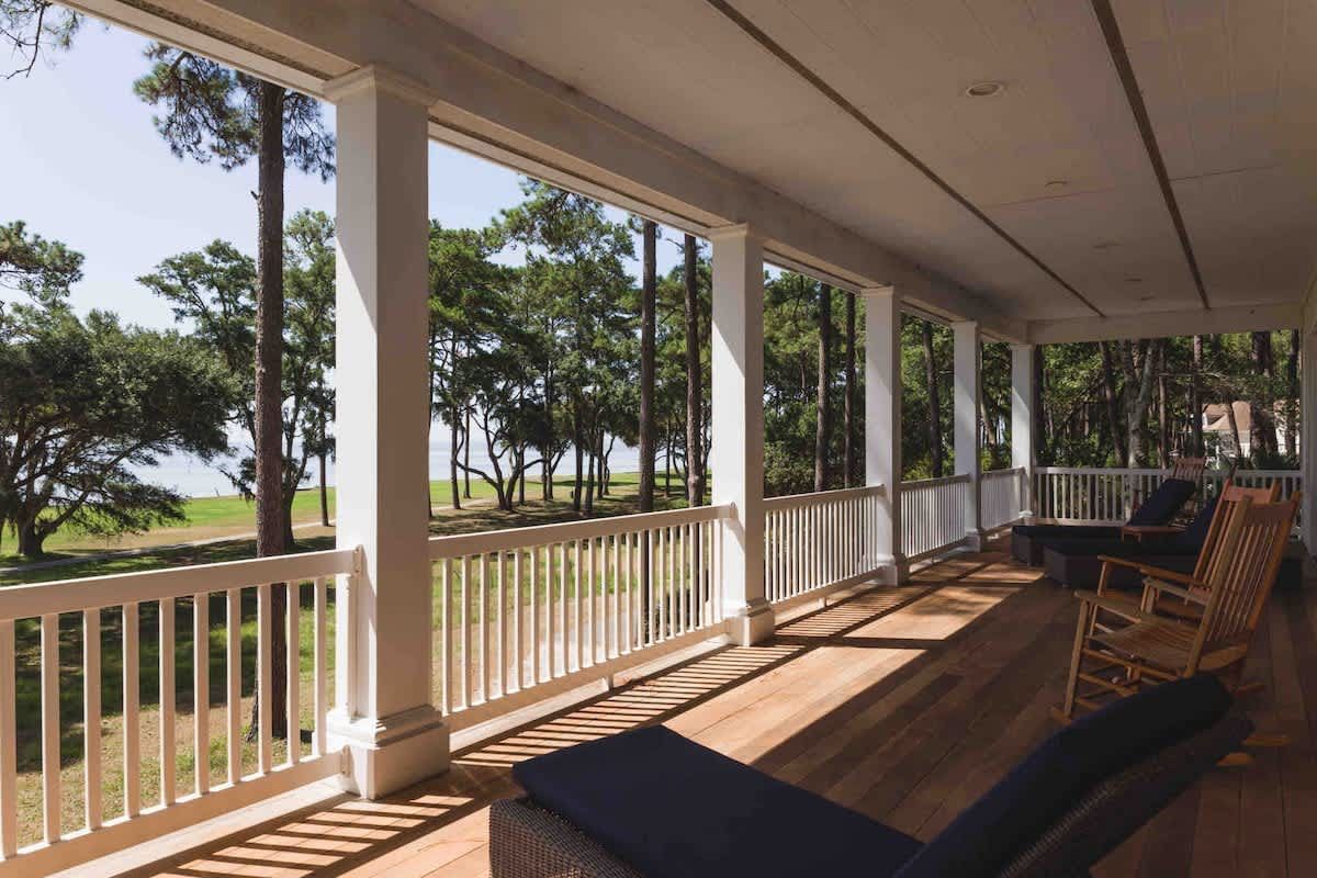There are many rocking chairs on the porch of a house.