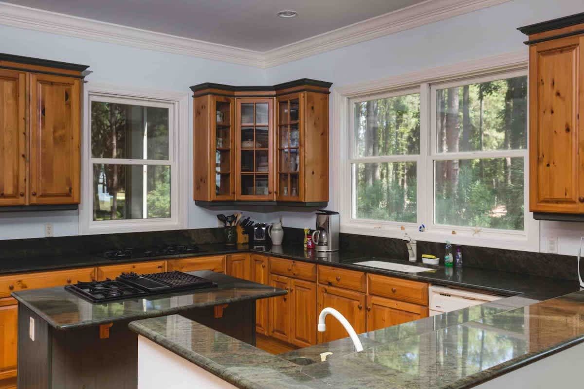 A porch with a row of white rocking chairs on it.