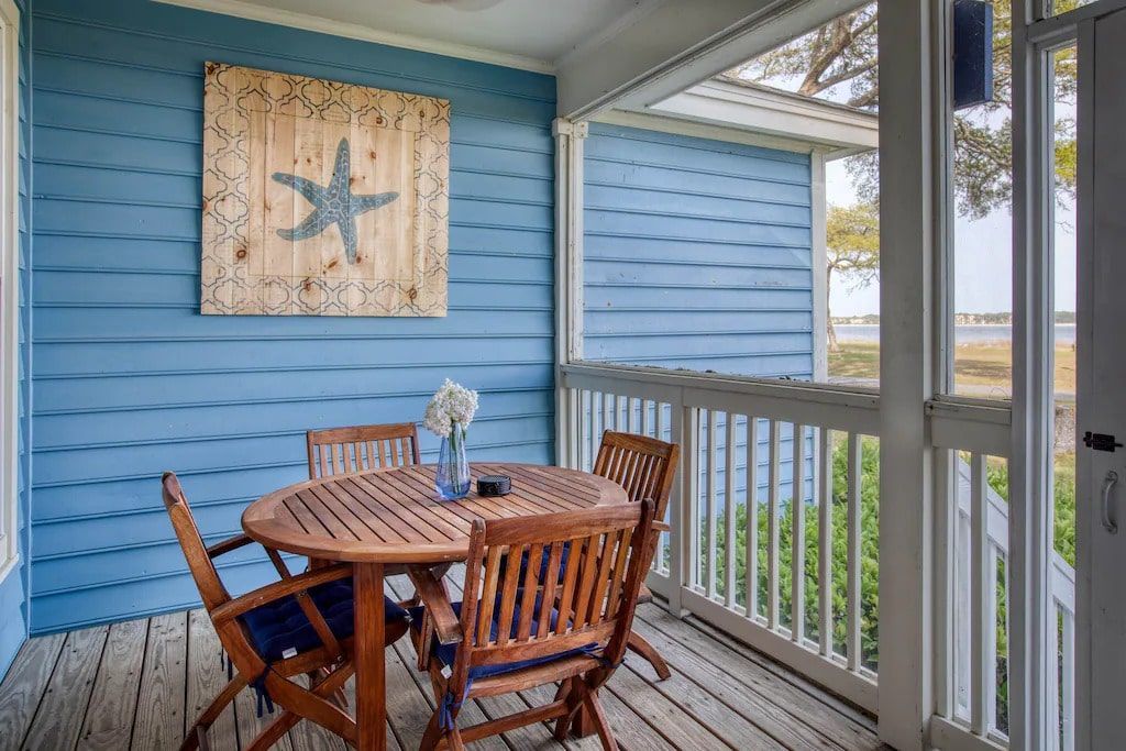 There is a table and chairs on the porch of a house.
