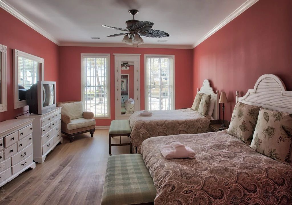 A bedroom with two beds and a ceiling fan