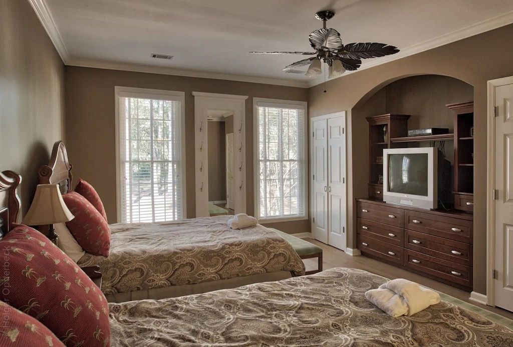 A bedroom with two beds a television and a ceiling fan