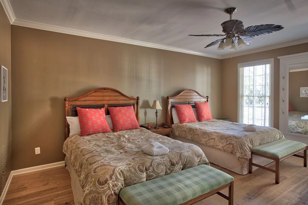 A bedroom with two beds and a ceiling fan