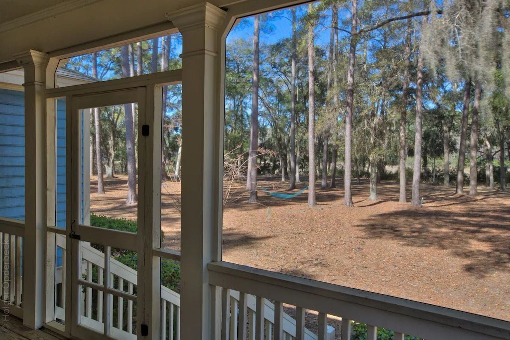 A screened in porch with a view of a forest.