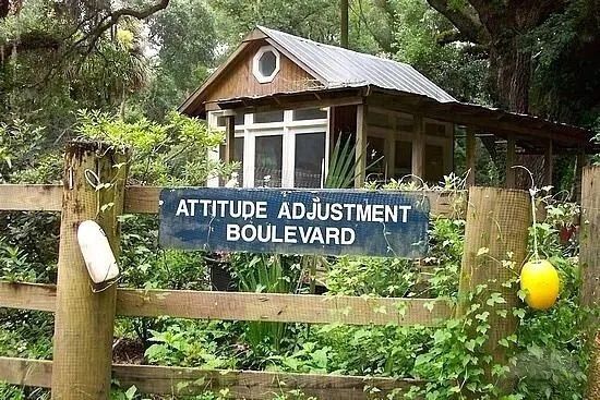 A wooden fence with a sign that says attitude adjustment boulevard
