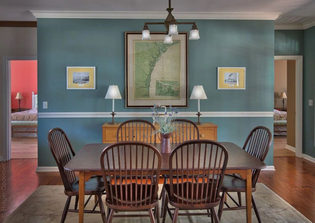 A dining room with a table and chairs and a picture on the wall